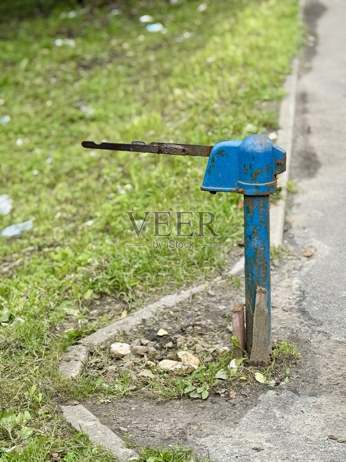 乡村水源,黎明时分,古老的铸铁水泵被乡村的杂草覆盖,古老的铸铁水泵独自矗立在龟裂的水泥地上,在宁静的乡村早晨照片摄影图片