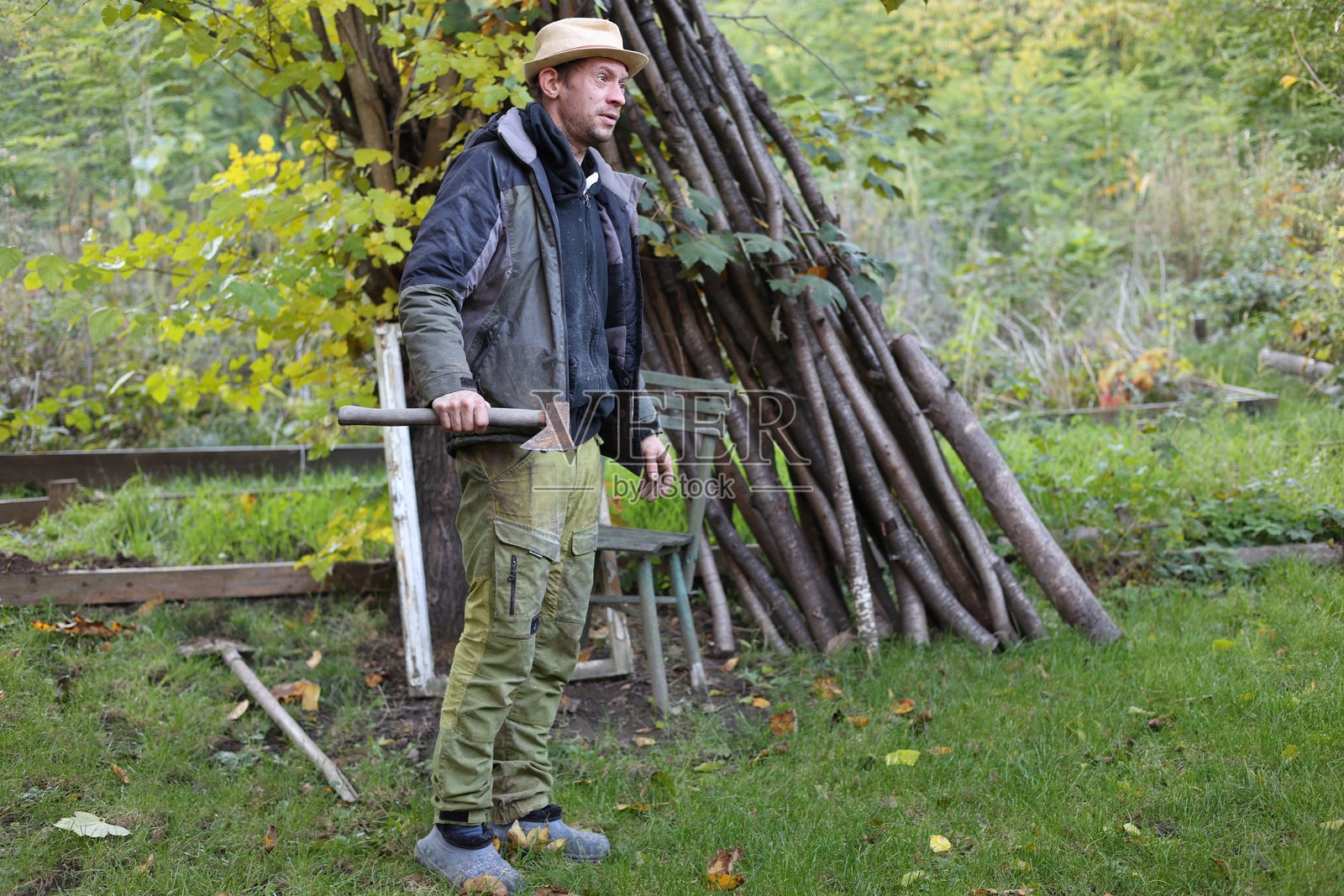 在自家花园里,一位乡村男子正在使用斧头砍柴。照片摄影图片