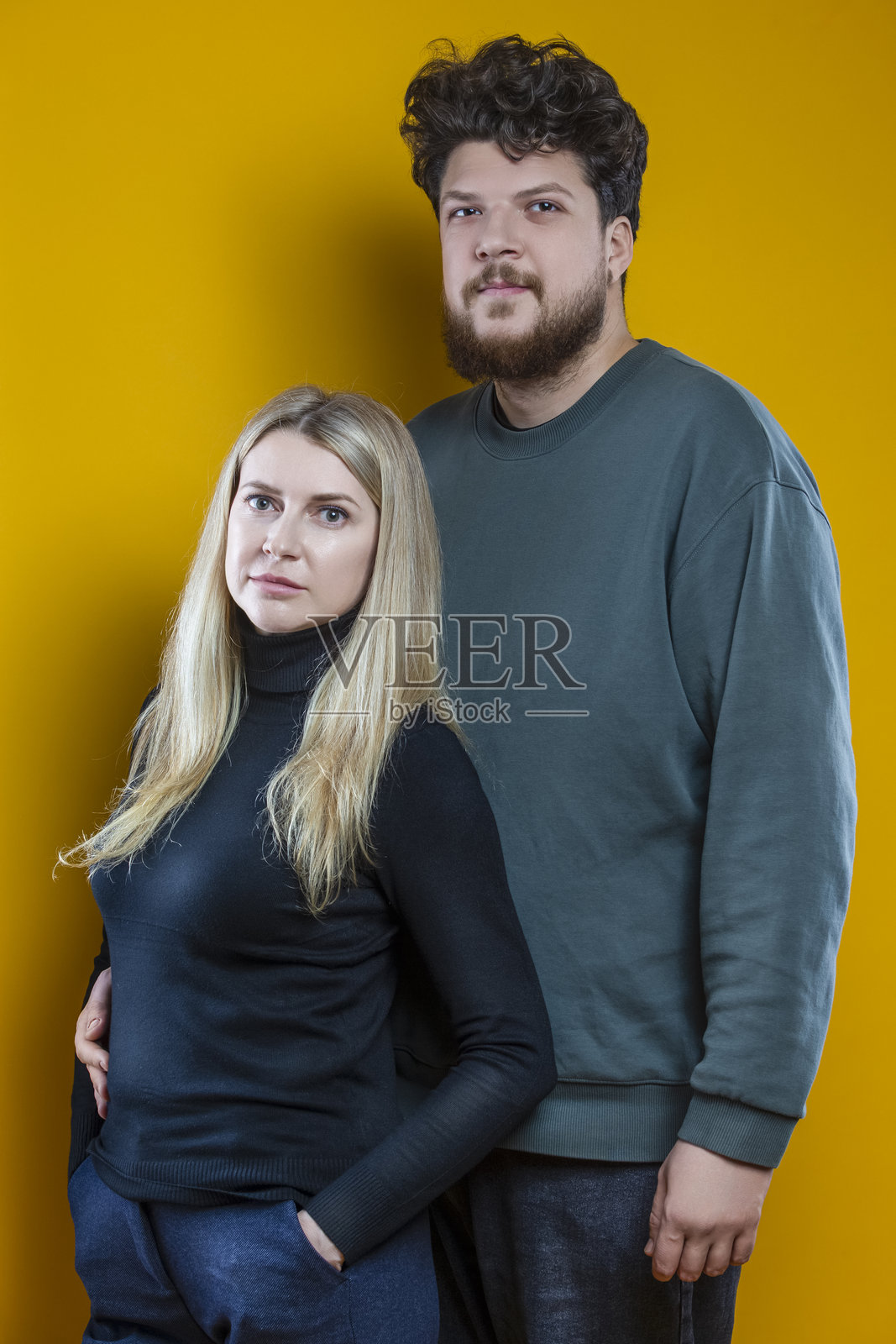 生活方式概念。年轻的白人情侣,面带微笑,可爱,如同友好的家庭,男女穿着休闲服饰,拥抱依偎,在无缝的黄色背景上孤立,作为工作室肖像。照片摄影图片