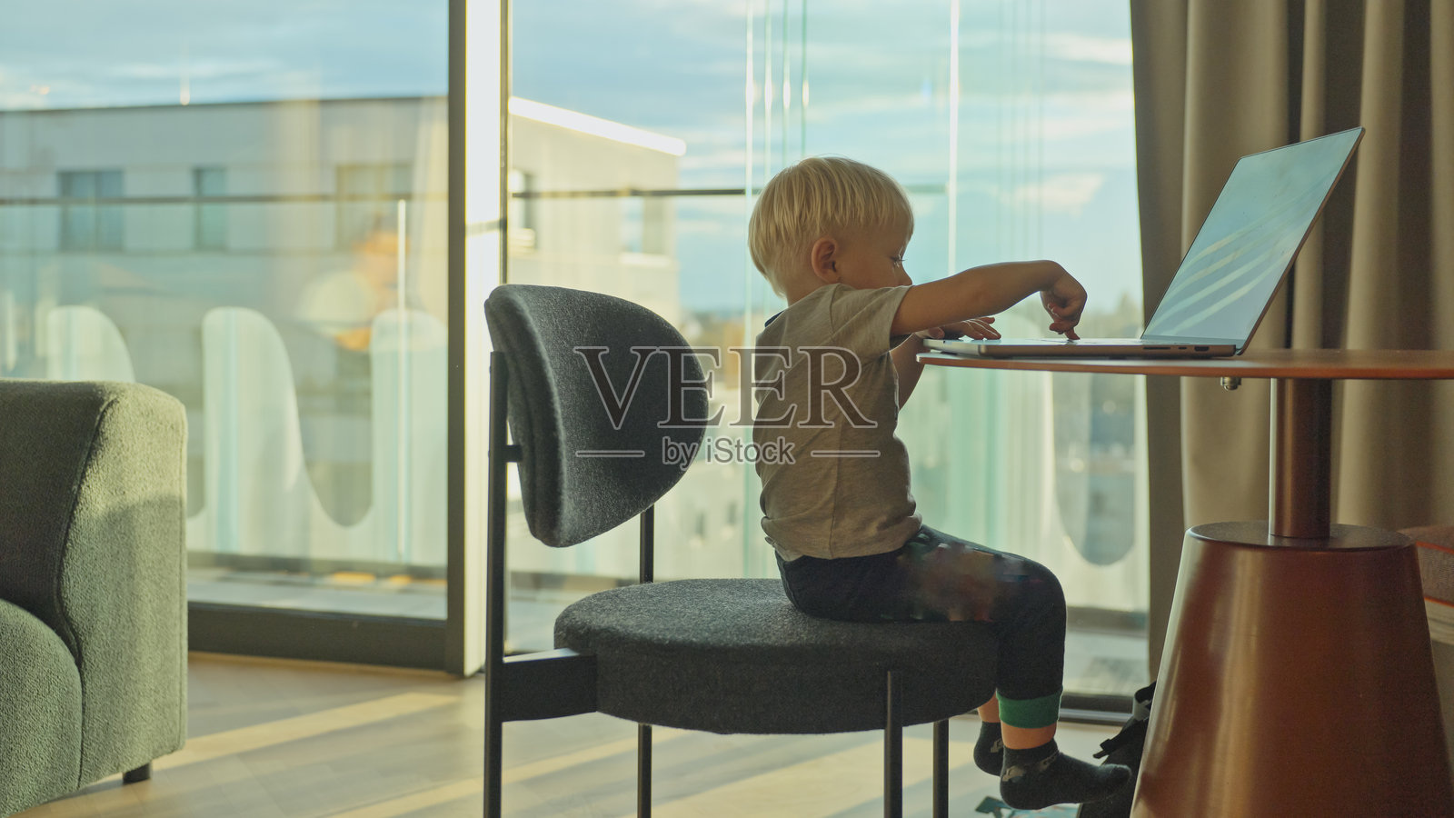 年轻的白人男孩在现代房间里兴致勃勃地模仿使用笔记本电脑照片摄影图片