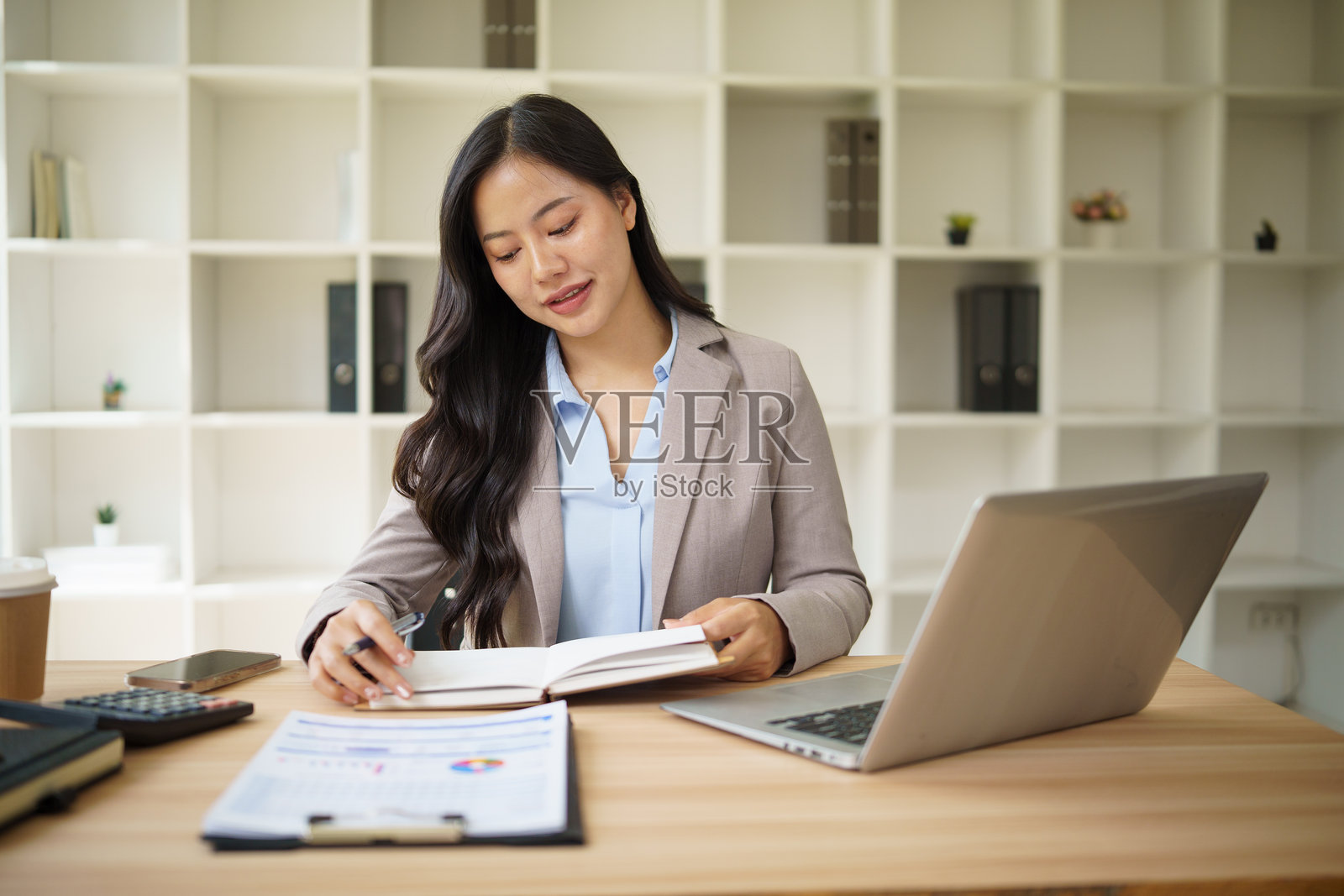 自信的女商人在笔记本上规划任务,享受工作。照片摄影图片