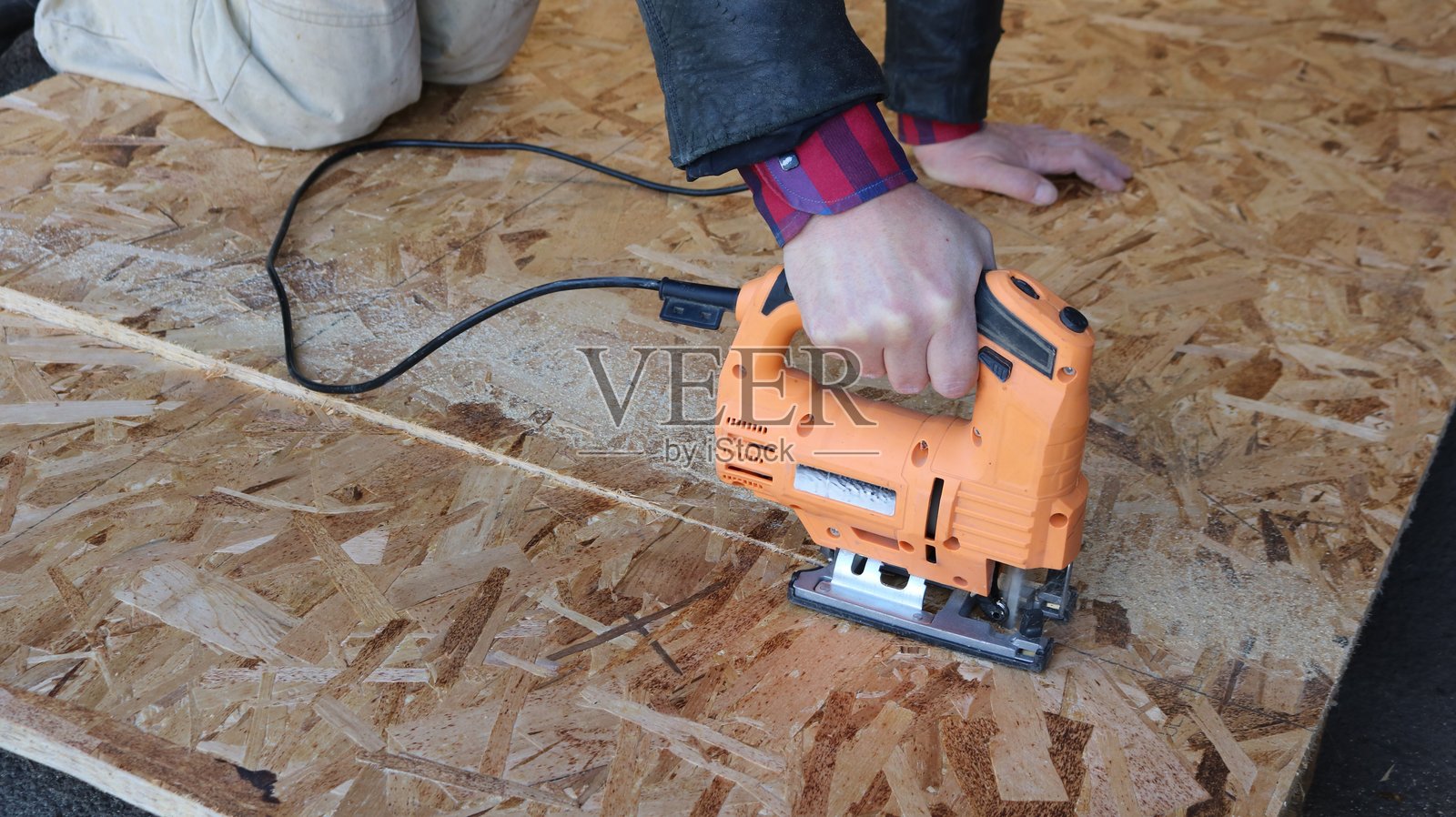 一位木匠正在使用曲线锯切割定向刨花板。照片摄影图片