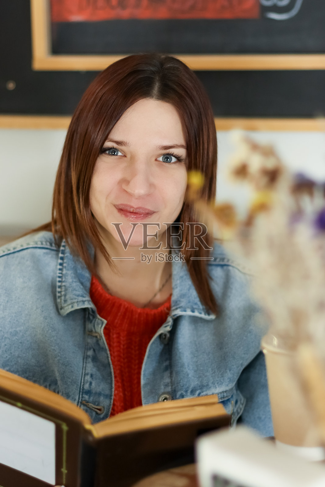 一位女性看向镜头,手中拿着一本打开的书照片摄影图片