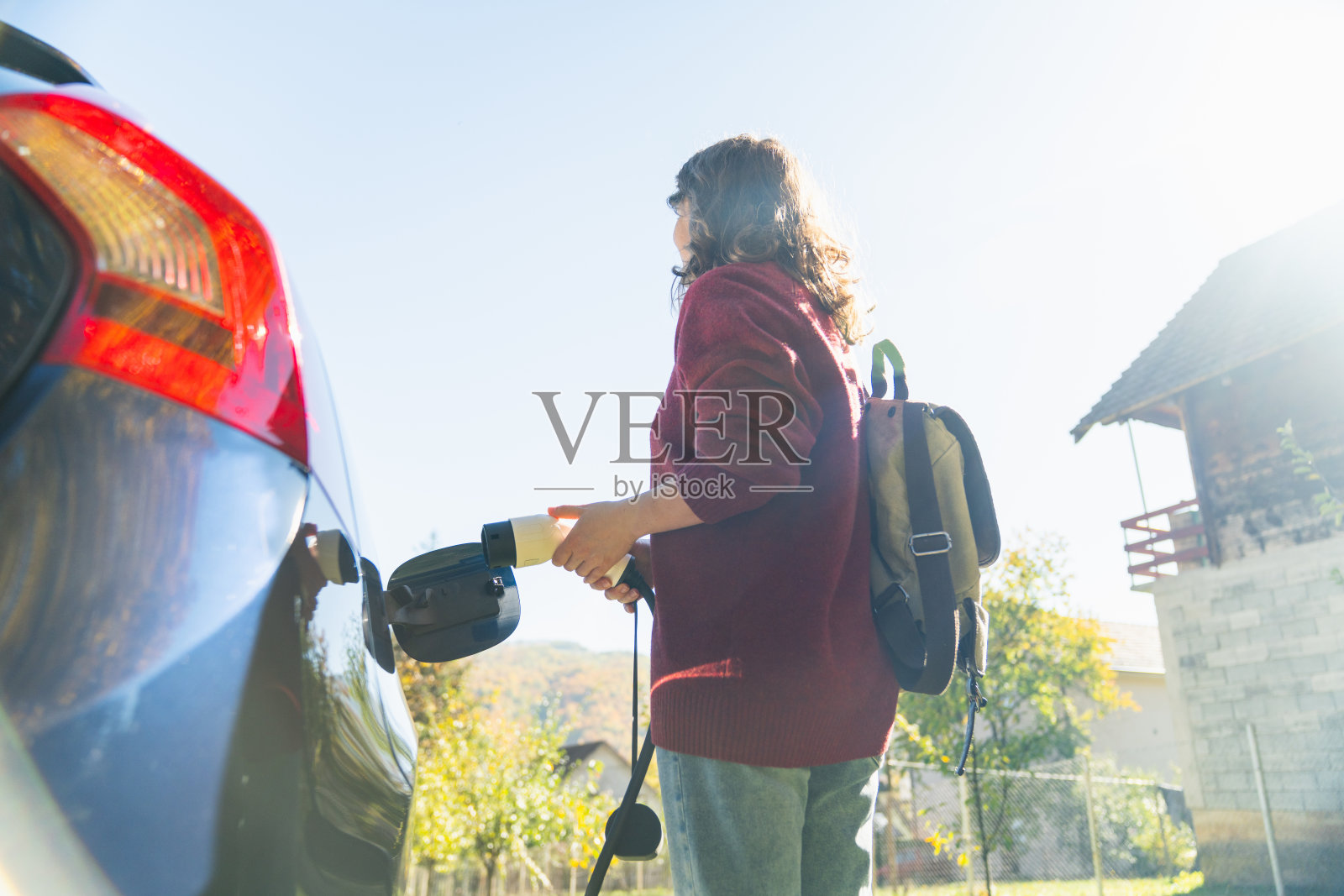 背着背包的女性旅行者站在充电电动车旁照片摄影图片