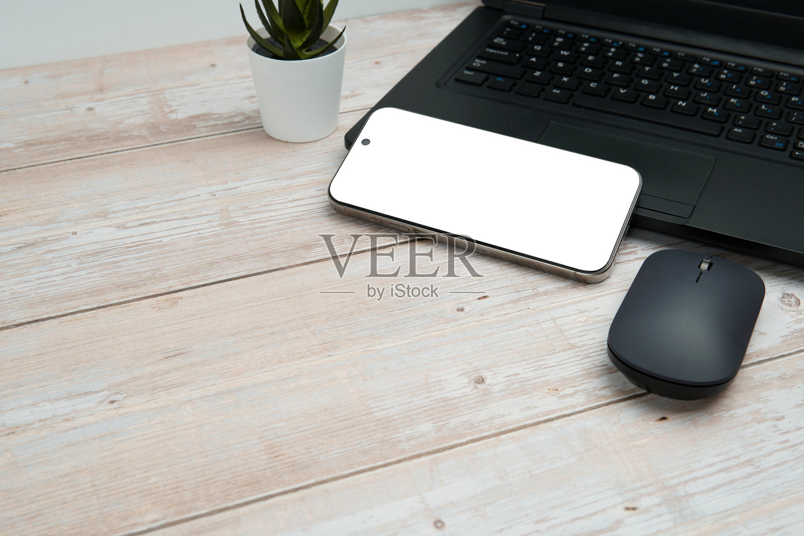 俯视角度的商务工作区,包含笔记本电脑、空白智能手机、鼠标和植物,摆放在白木桌上,代表着高效、数字化工作、模型展示和带有干净复制空间的专业办公设置。照片摄影图片