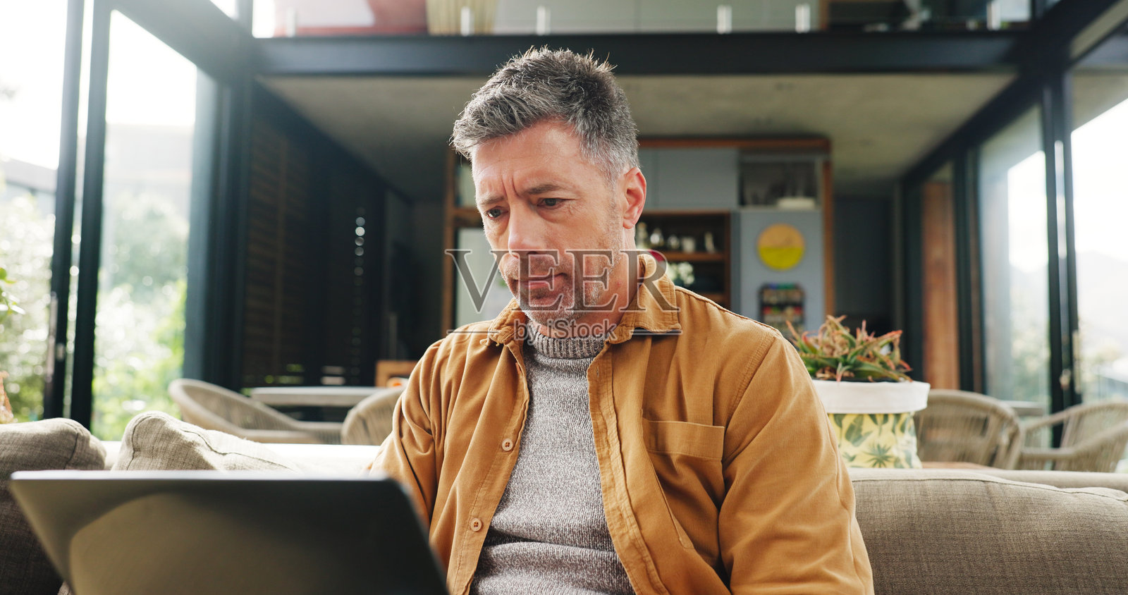 笔记本电脑,远程工作和研究,男人在客厅沙发上进行在线规划。电脑,电子邮件和打字,成熟的自由职业者在公寓里为小型企业初创公司工作照片摄影图片