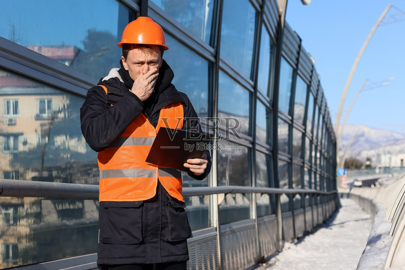 一名沮丧的工人在看笔记时捂着鼻子照片摄影图片