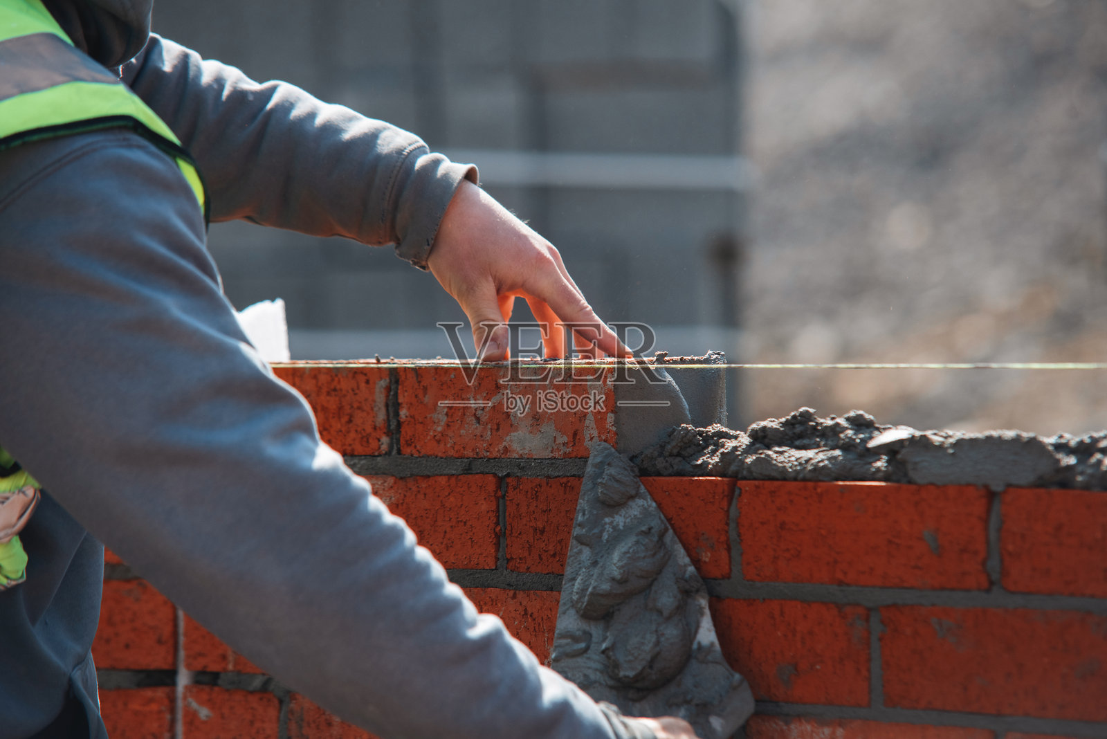 建筑工地上熟练的砌砖工特写,正在墙上砌一块红砖照片摄影图片