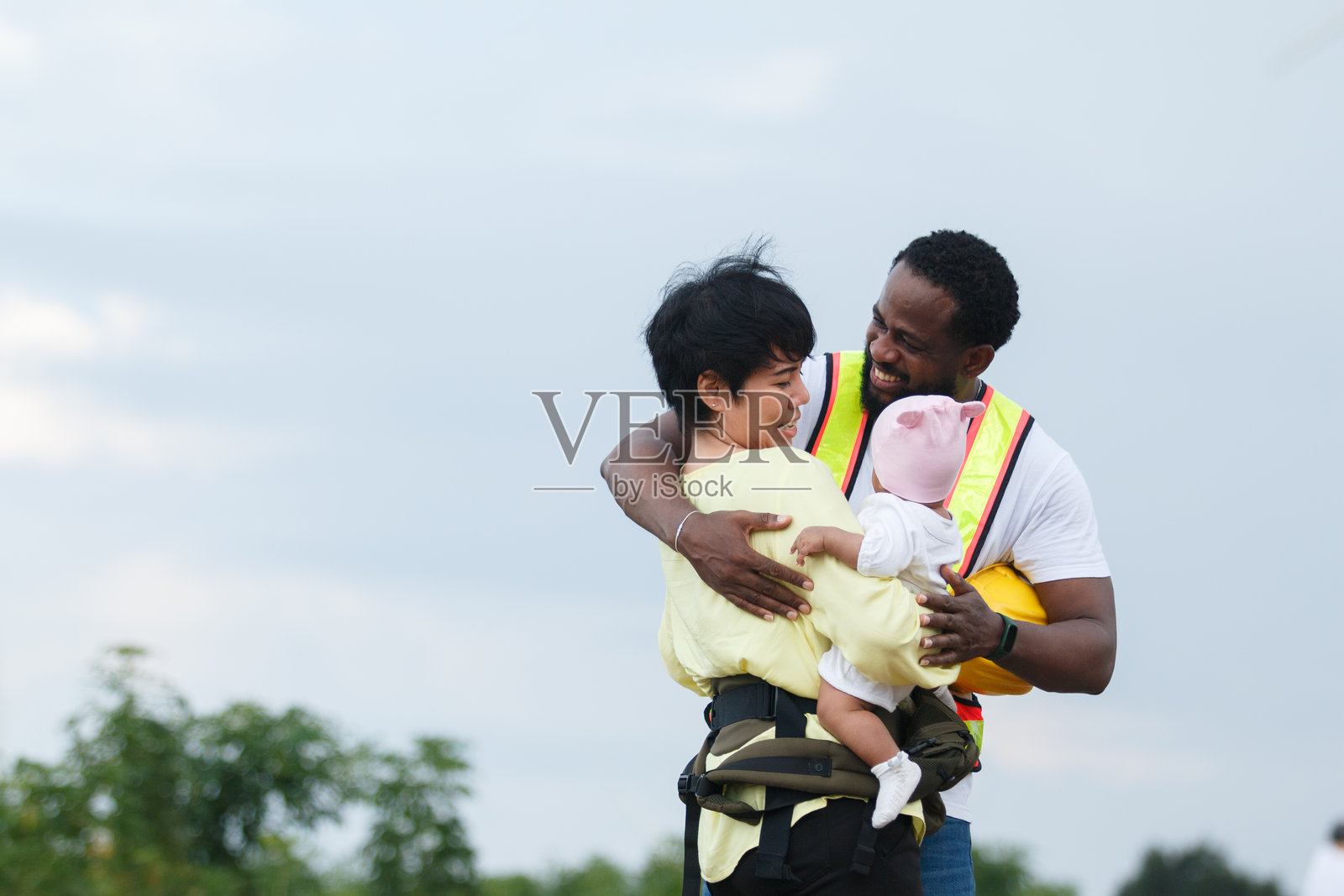 辛勤工作的父亲与婴儿和母亲共享温馨的家庭时光。工作与生活平衡、安全、多元化和育儿的概念。照片摄影图片