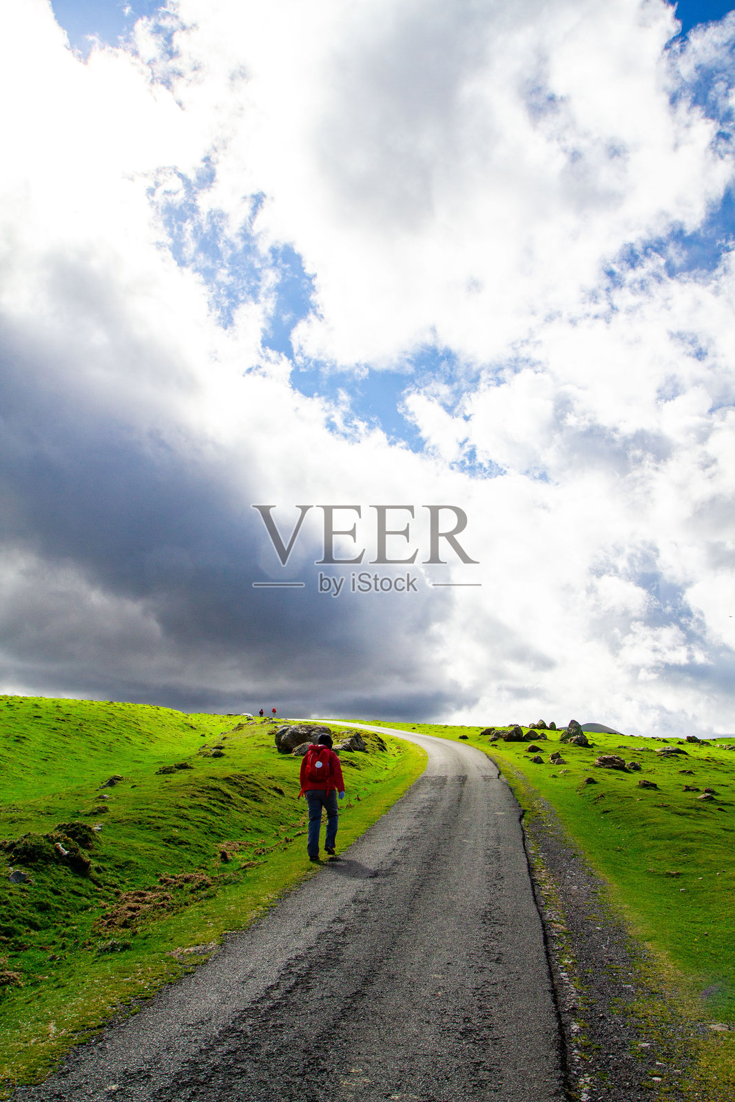 一位女子漫步在法国南部山区,郁郁葱葱的绿色山坡在晴朗的蓝天下延绵起伏。照片摄影图片