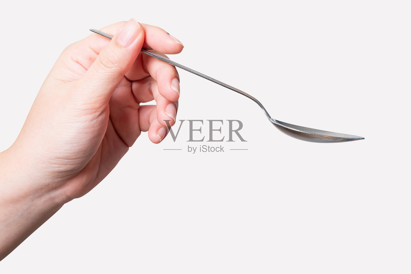 一把银色钢勺被一只女性的手握住,孤立在背景上。照片摄影图片
