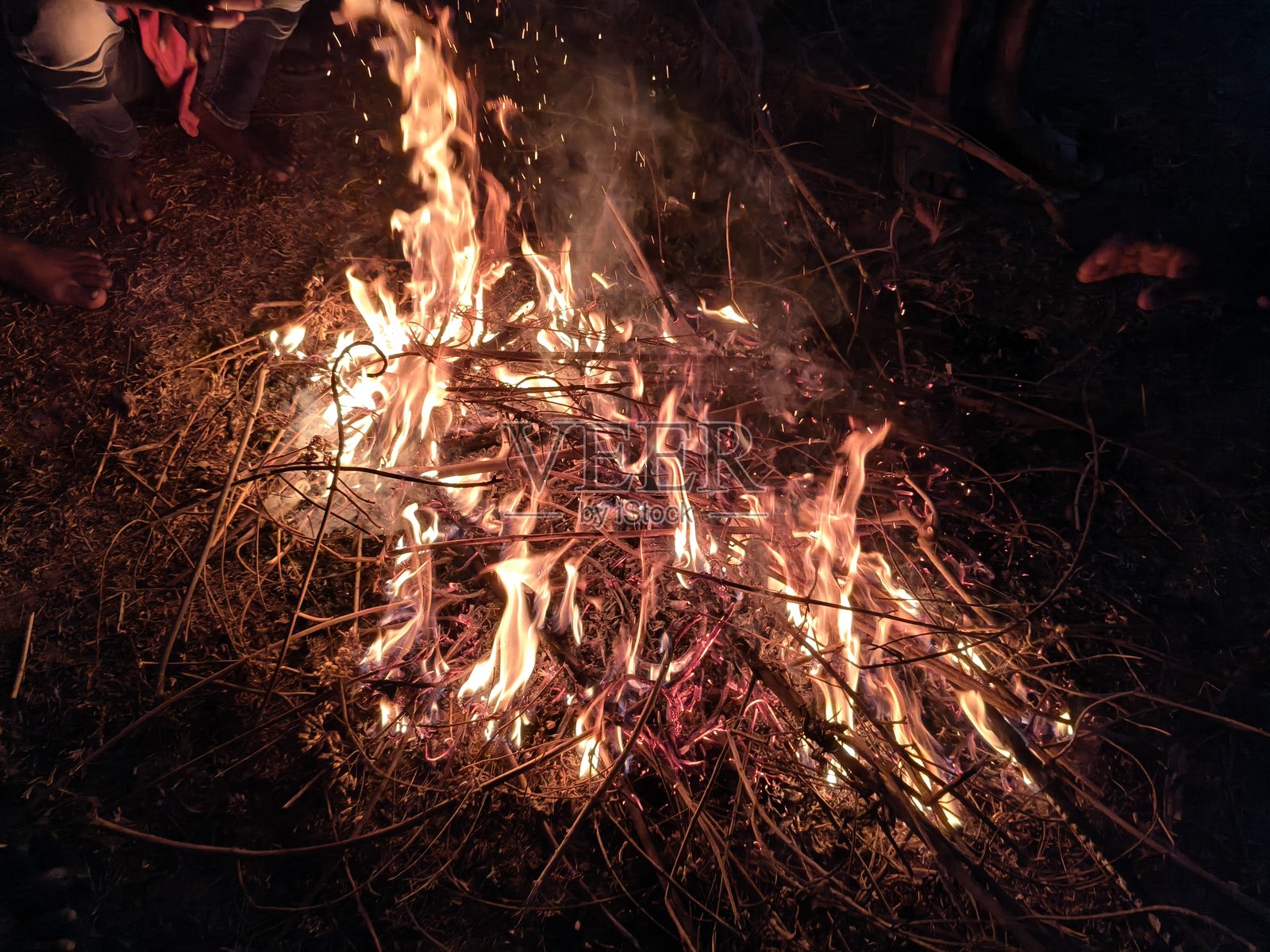 人们围坐在篝火旁,烘烤着双手和双脚。照片摄影图片