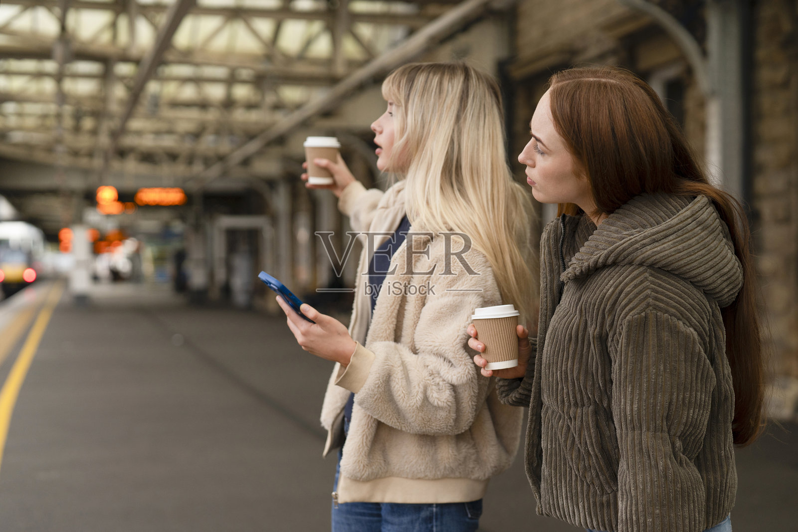 下午,朋友们在火车站等待,一边寻找火车一边查看手机照片摄影图片