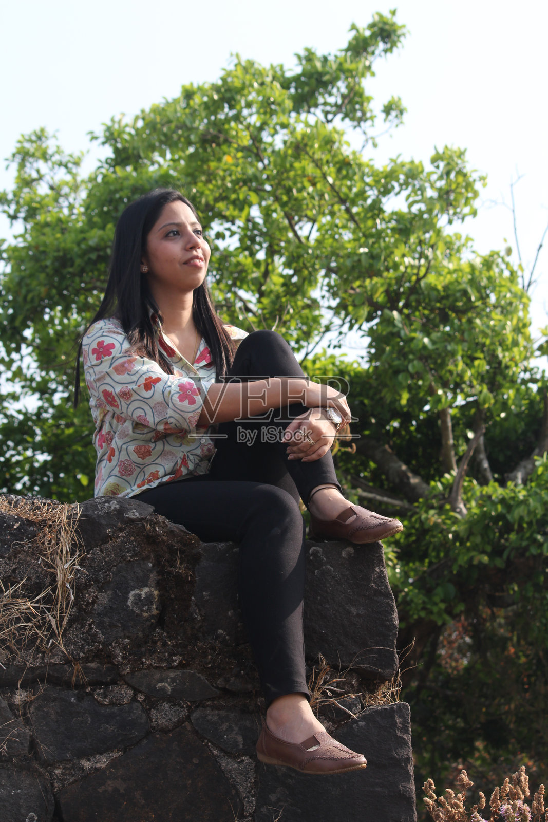 年轻女子坐在岩石上,享受大自然照片摄影图片