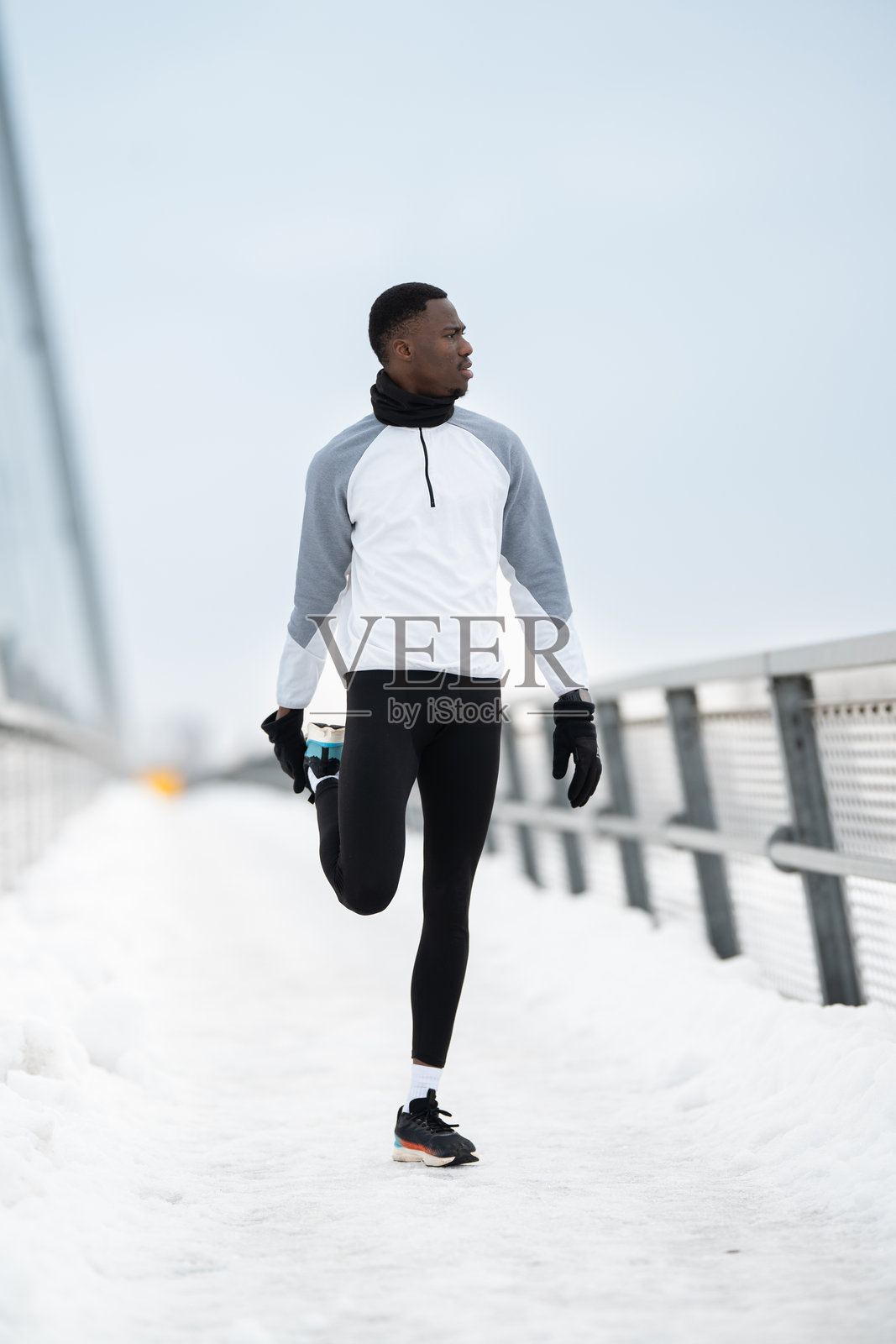 一名男性跑者在雪地户外小径上拉伸腿部照片摄影图片