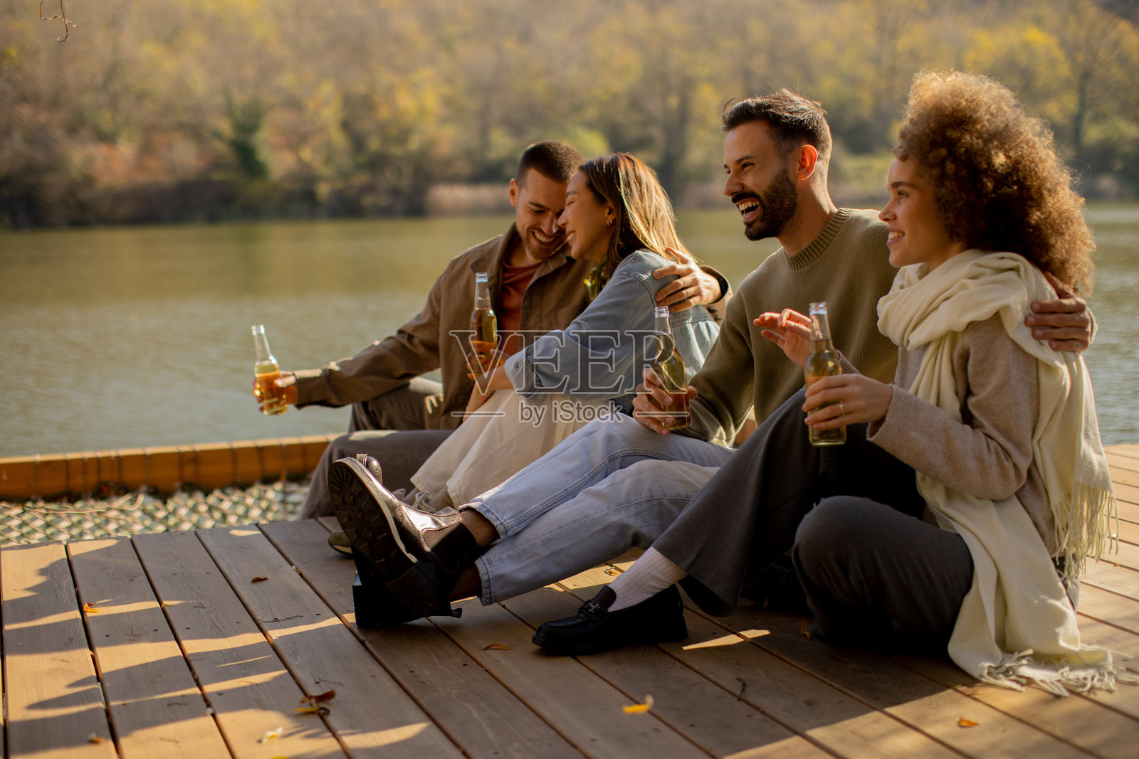 秋日里,朋友们手持酒杯,在湖边享受悠闲的夜晚照片摄影图片