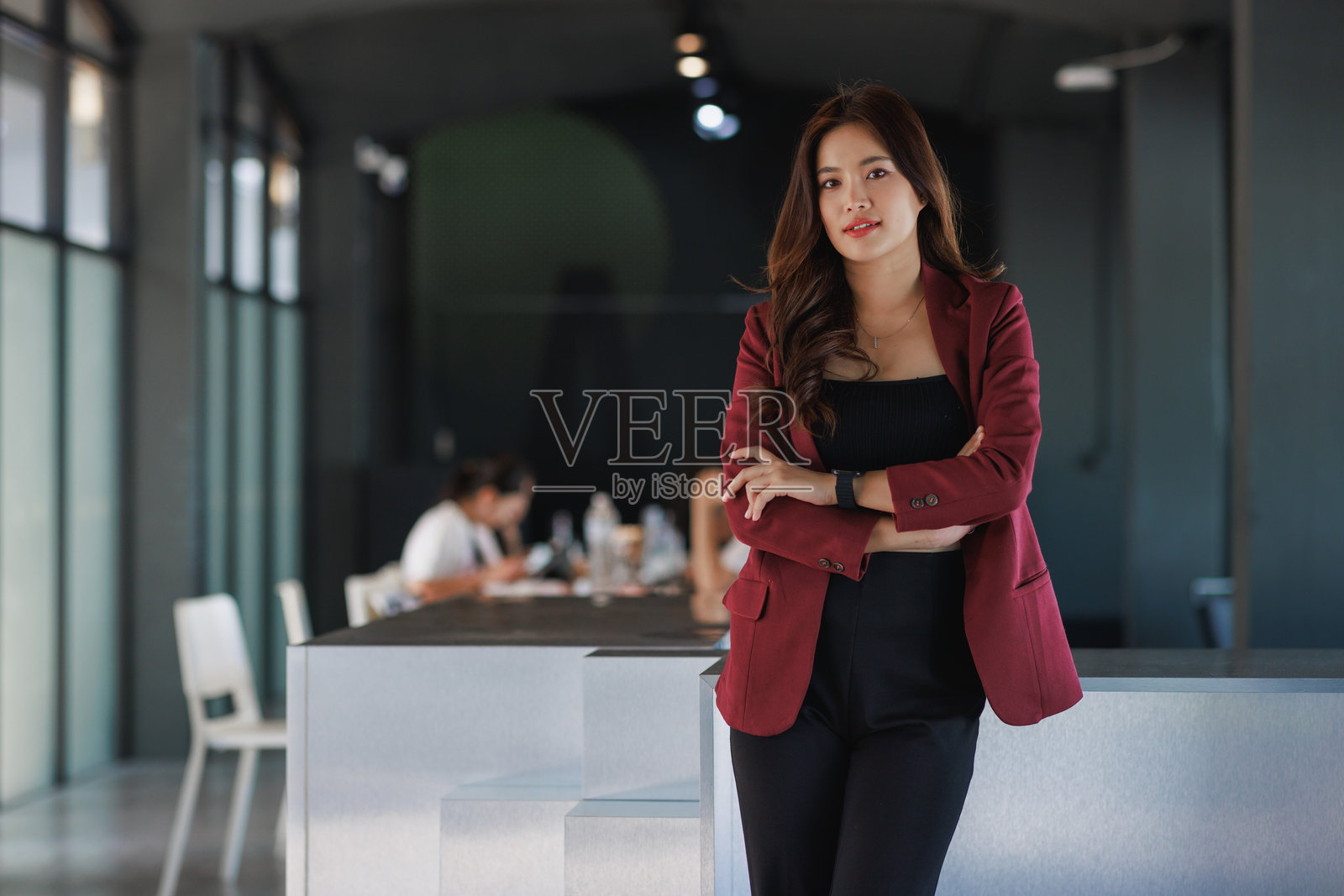 一位年轻的亚洲女商人在办公室里双臂交叉站立照片摄影图片