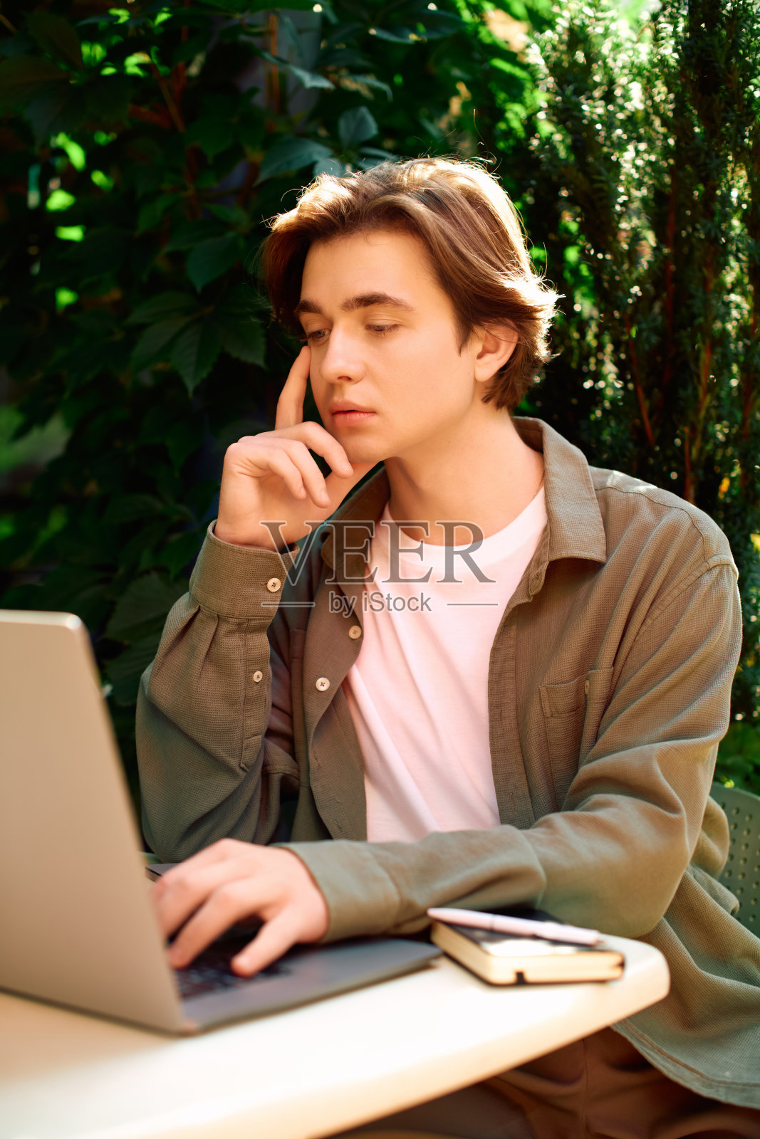 年轻男子在绿植环绕的现代咖啡馆里专注地使用笔记本电脑照片摄影图片