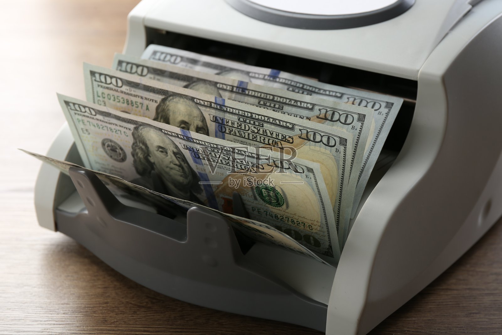 木桌上的美元钞票数钞机,特写照片摄影图片