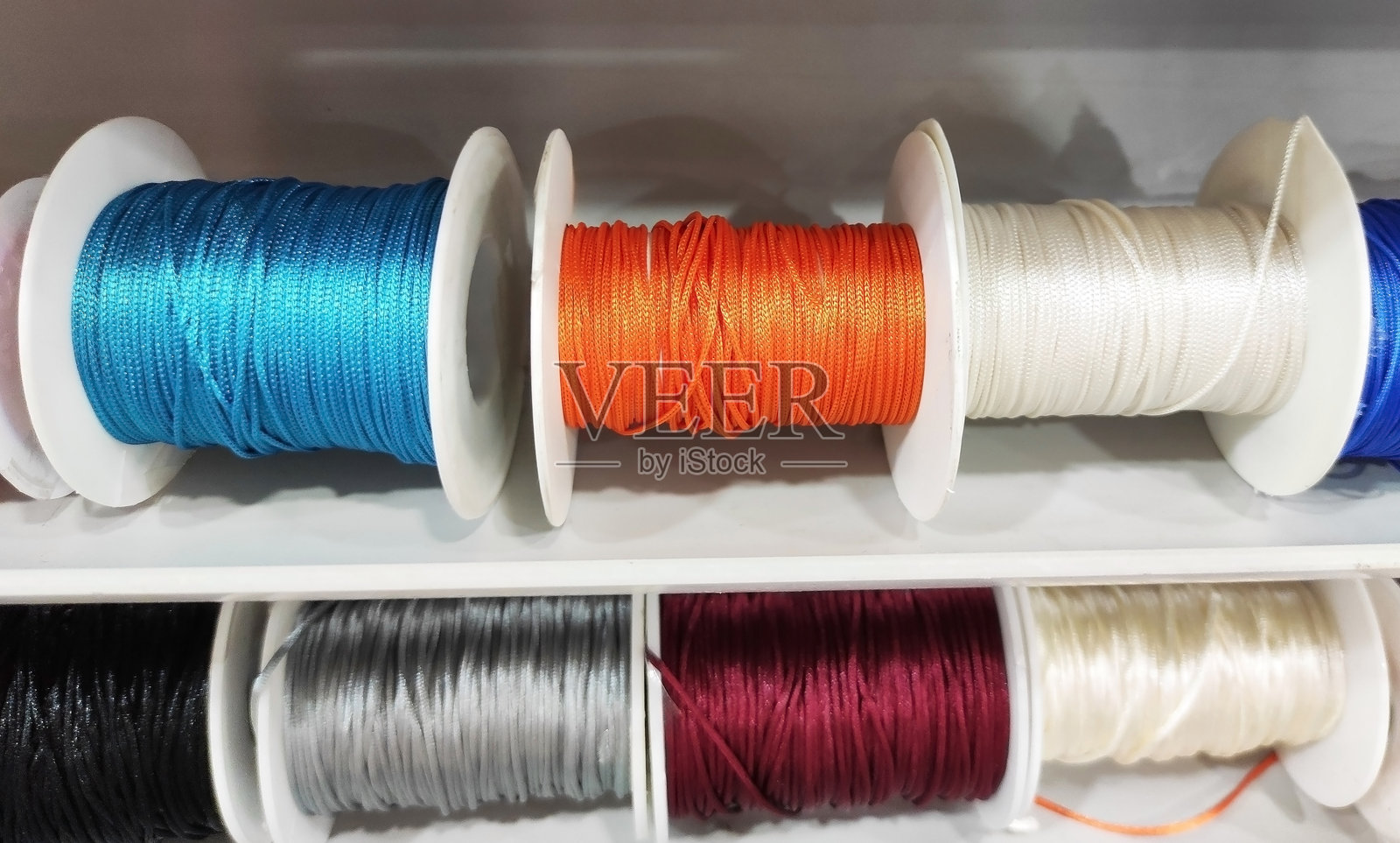 商店货架上陈列着彩色的线轴,适合用于缝纫、针织、裁缝、纺织生产和创意设计。照片摄影图片