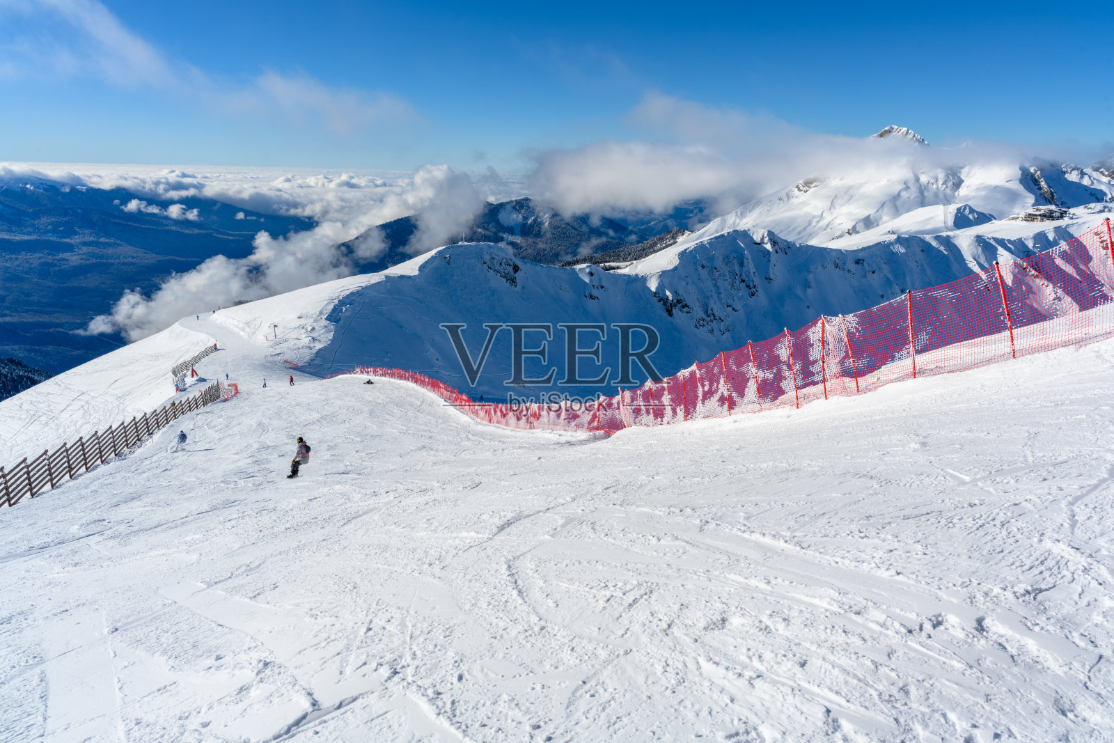 红色的栅栏沿着滑雪道延伸,远处是连绵的山峦。照片摄影图片
