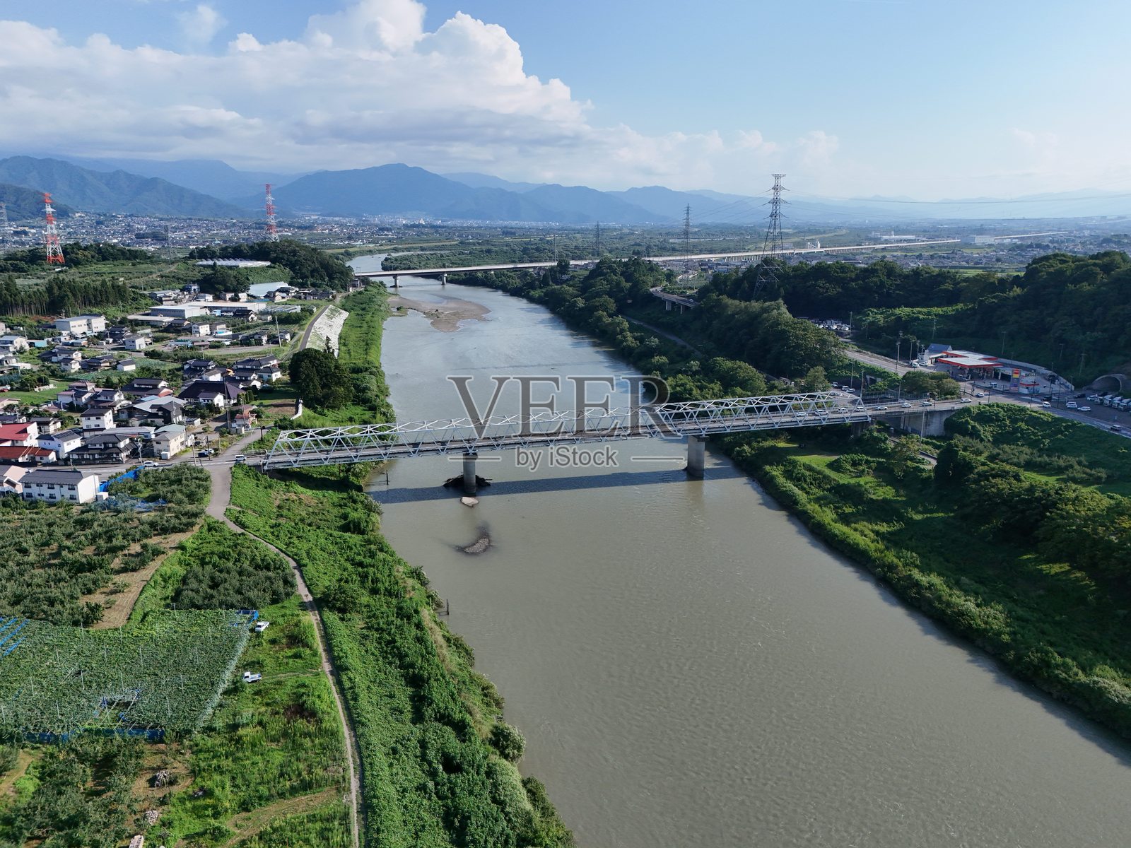 一座桥横跨河流,背景是绿色和棕色的风景。照片摄影图片