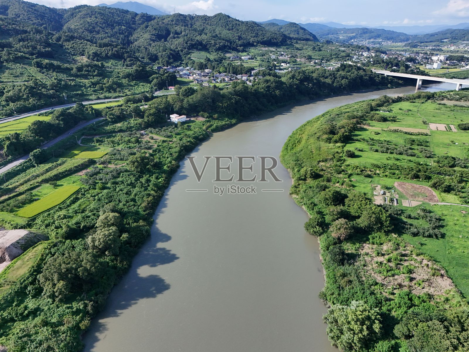 一座桥梁横跨河流,河对岸是绿色的田野。照片摄影图片