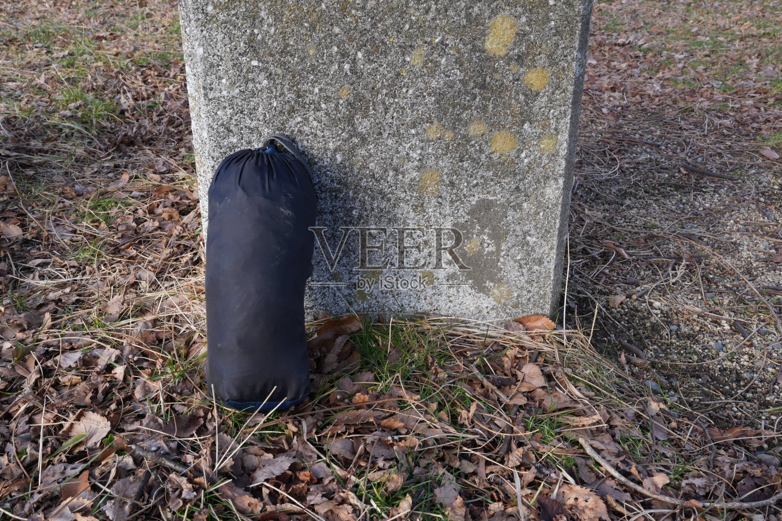 一个黑色的睡袋放在地上,旁边有一块大石头照片摄影图片