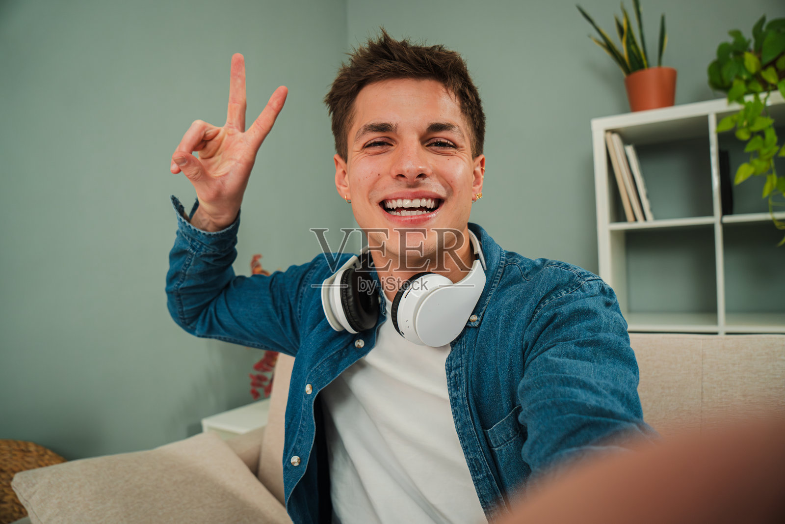 年轻男子在家微笑自拍。友好的男孩在客厅里看着镜头,露出完美的白牙笑容。真实的白人男性个人肖像。照片摄影图片