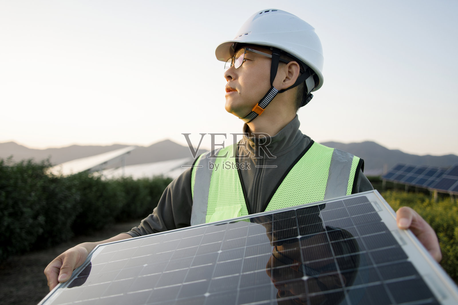 工程师手持光伏板眺望太阳能电站照片摄影图片