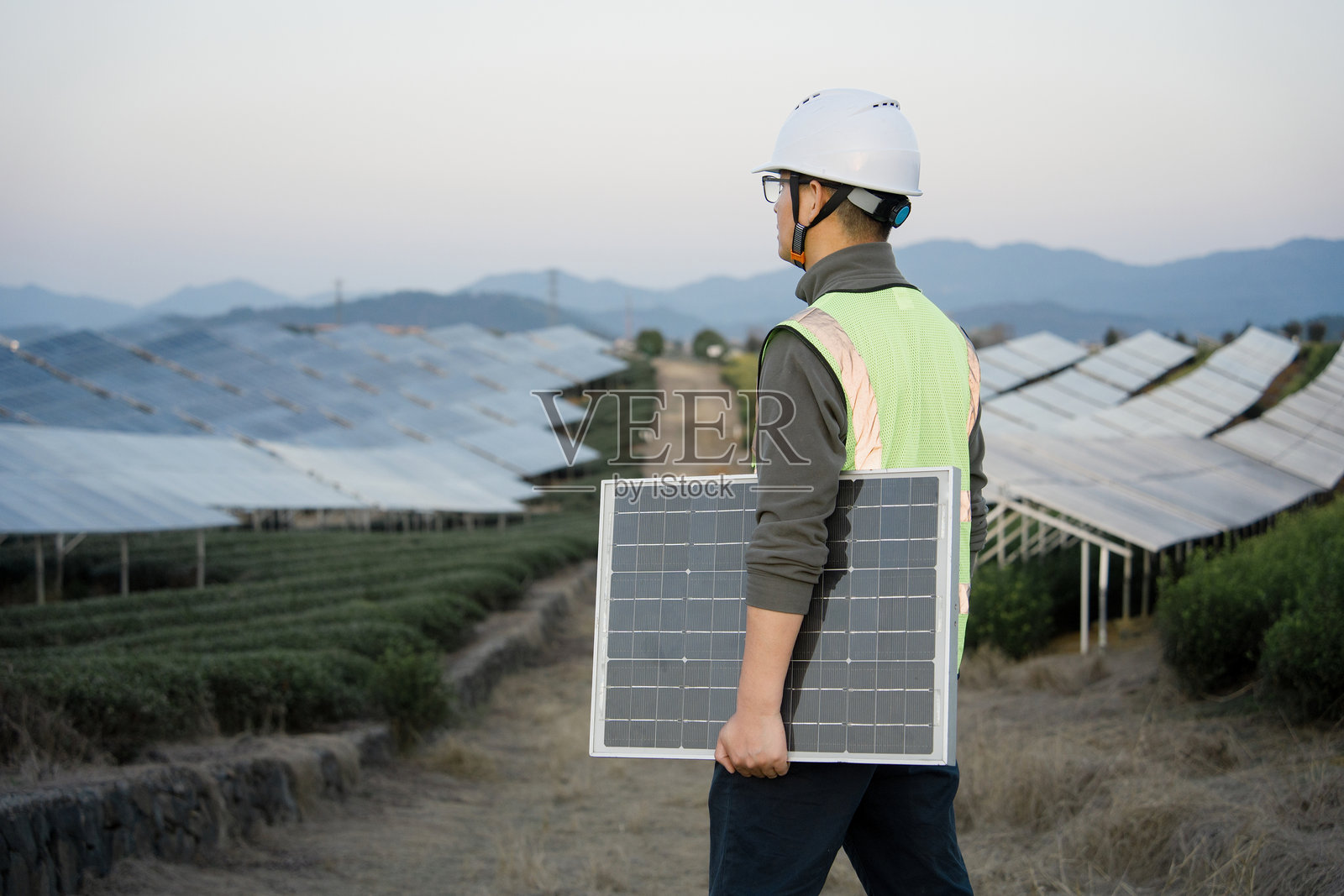 工程师持光伏板巡视山地光伏电站照片摄影图片