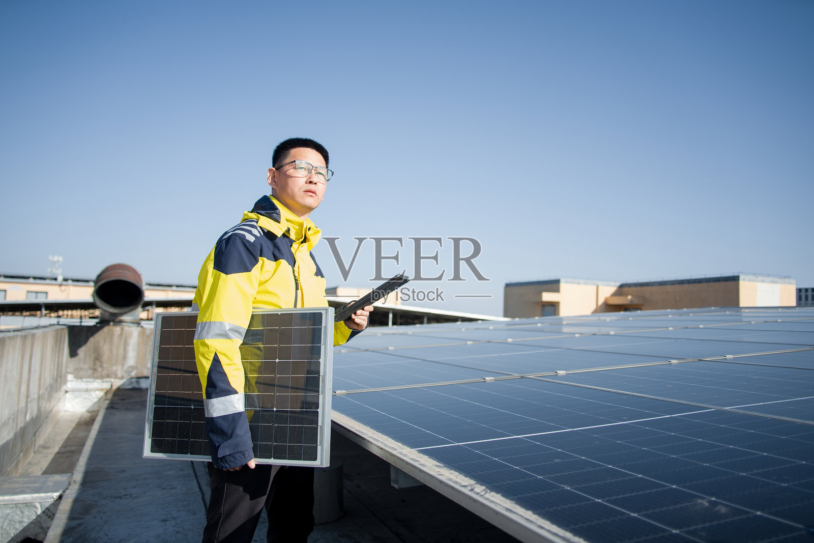 工程师手持光伏板检查屋顶太阳能阵列照片摄影图片