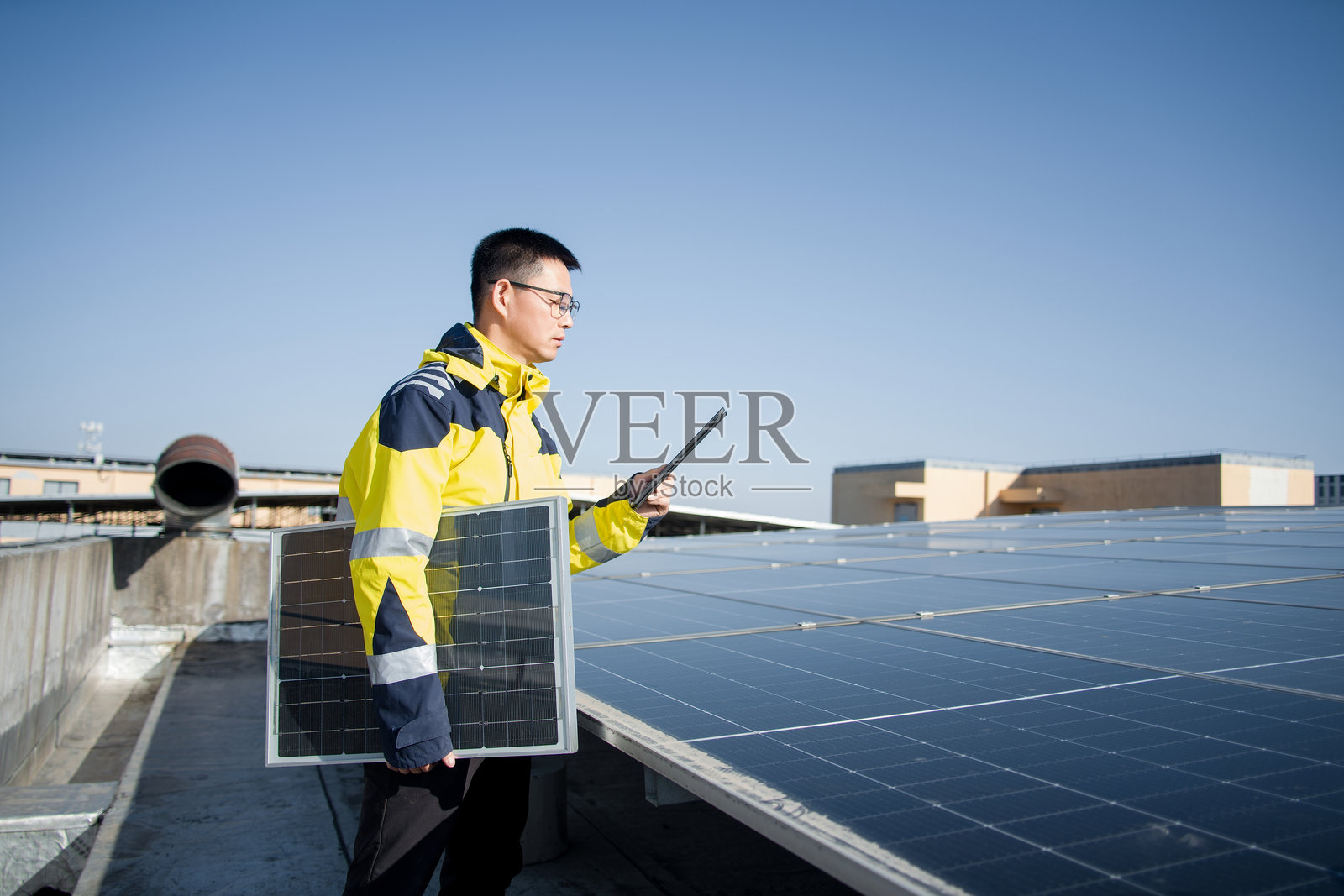 工程师手持光伏板检查屋顶太阳能阵列照片摄影图片
