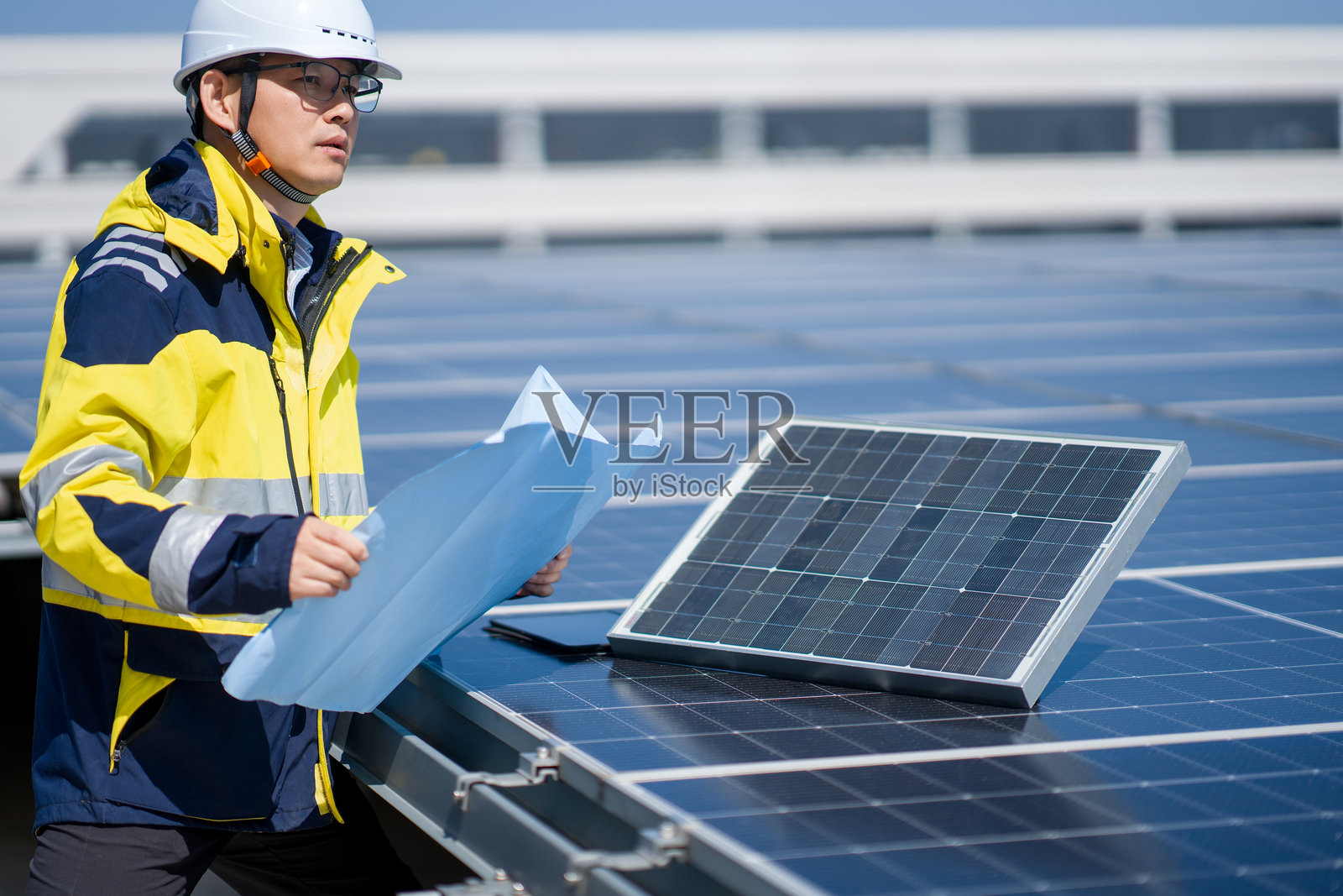 工程师检查屋顶光伏板并查阅图纸照片摄影图片
