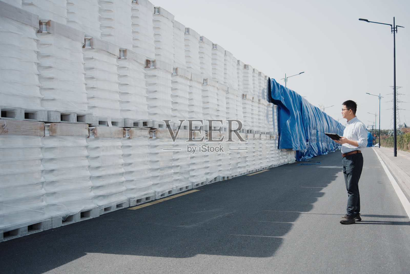 男子手持平板检查路边白色货垛照片摄影图片