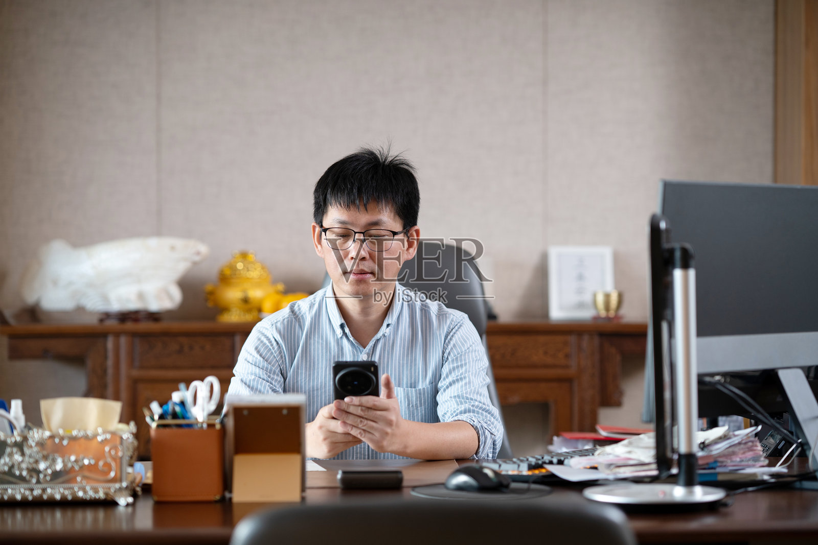 中年男士坐办公室看手机照片摄影图片