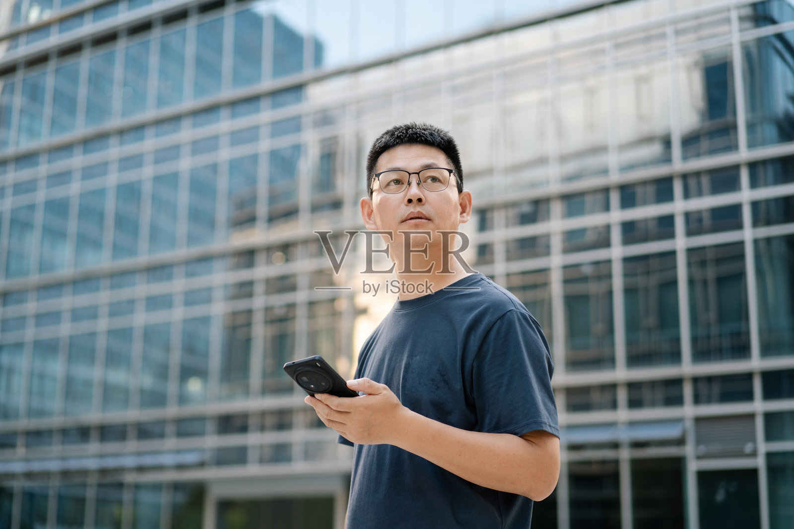 商务楼前男子持手机照片摄影图片