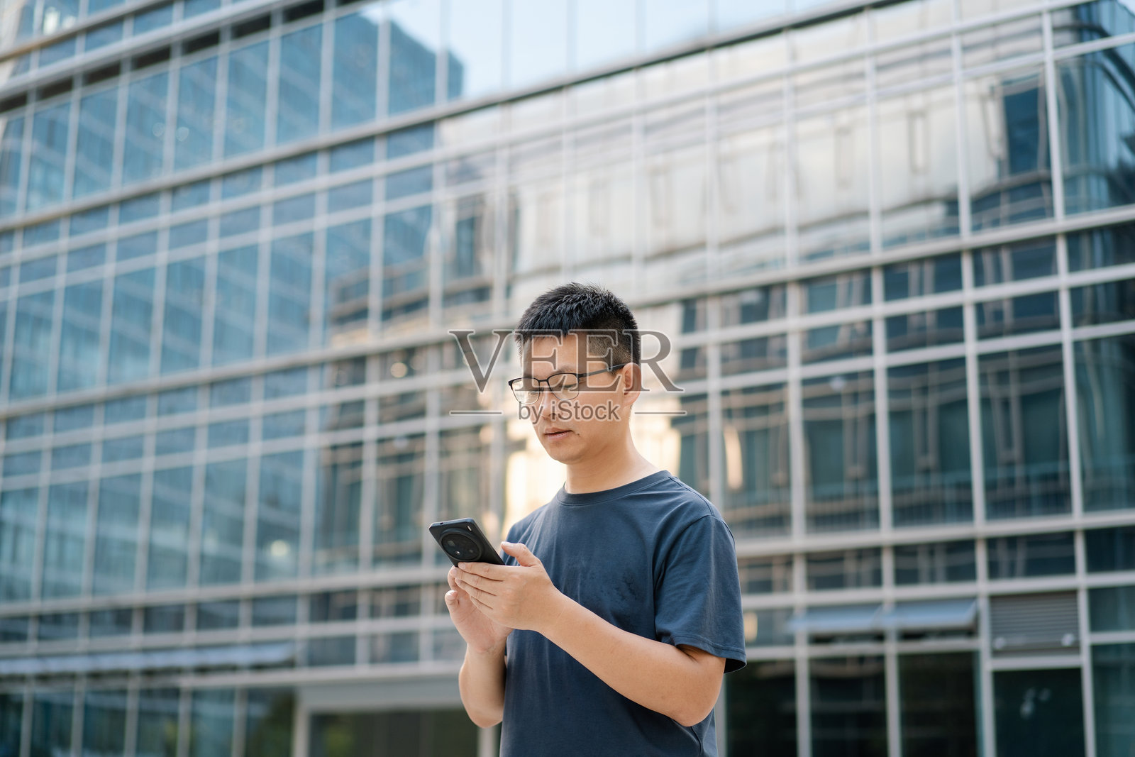 商务楼前男子看手机照片摄影图片
