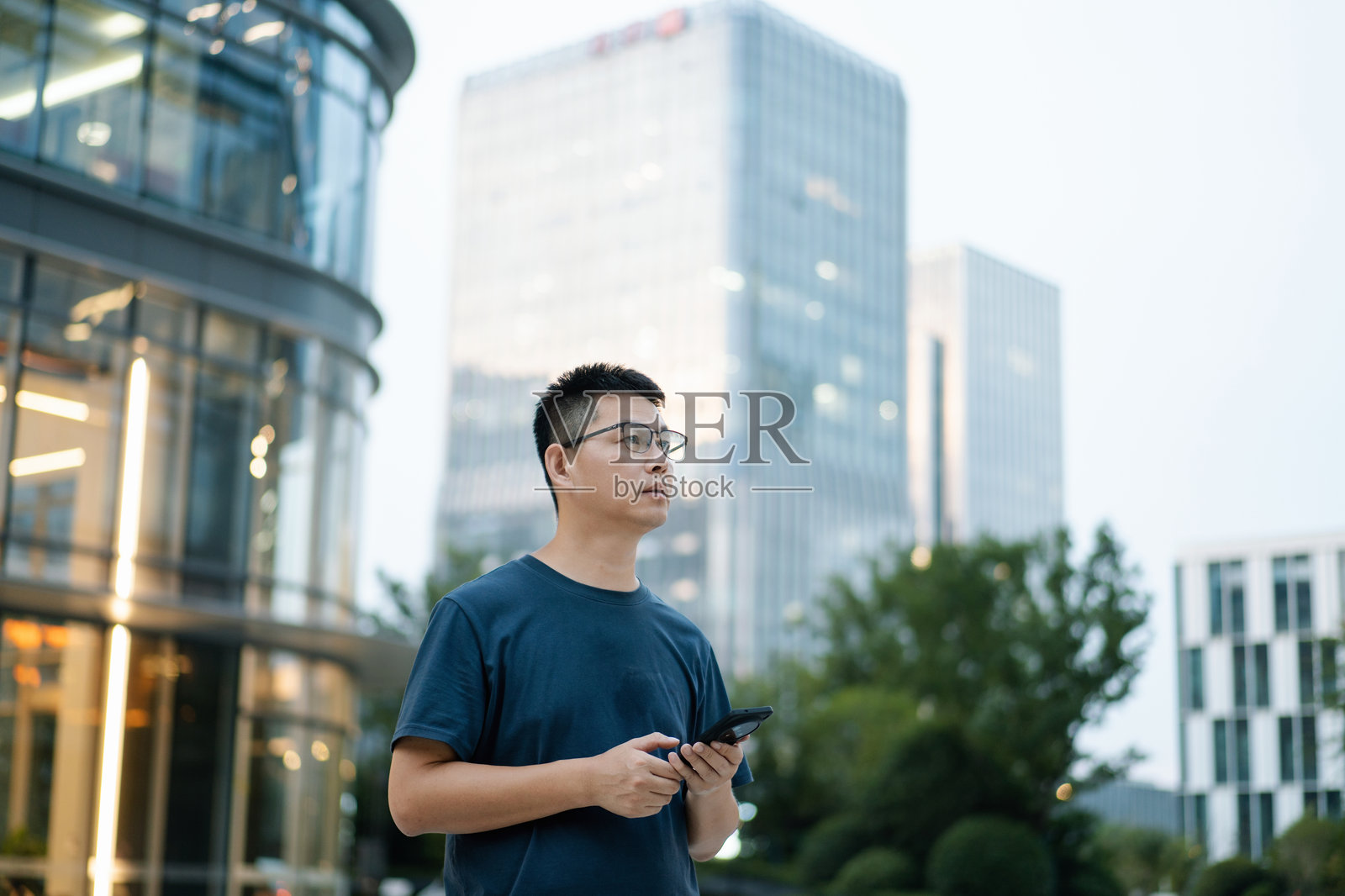 商务男士持手机站商务区照片摄影图片