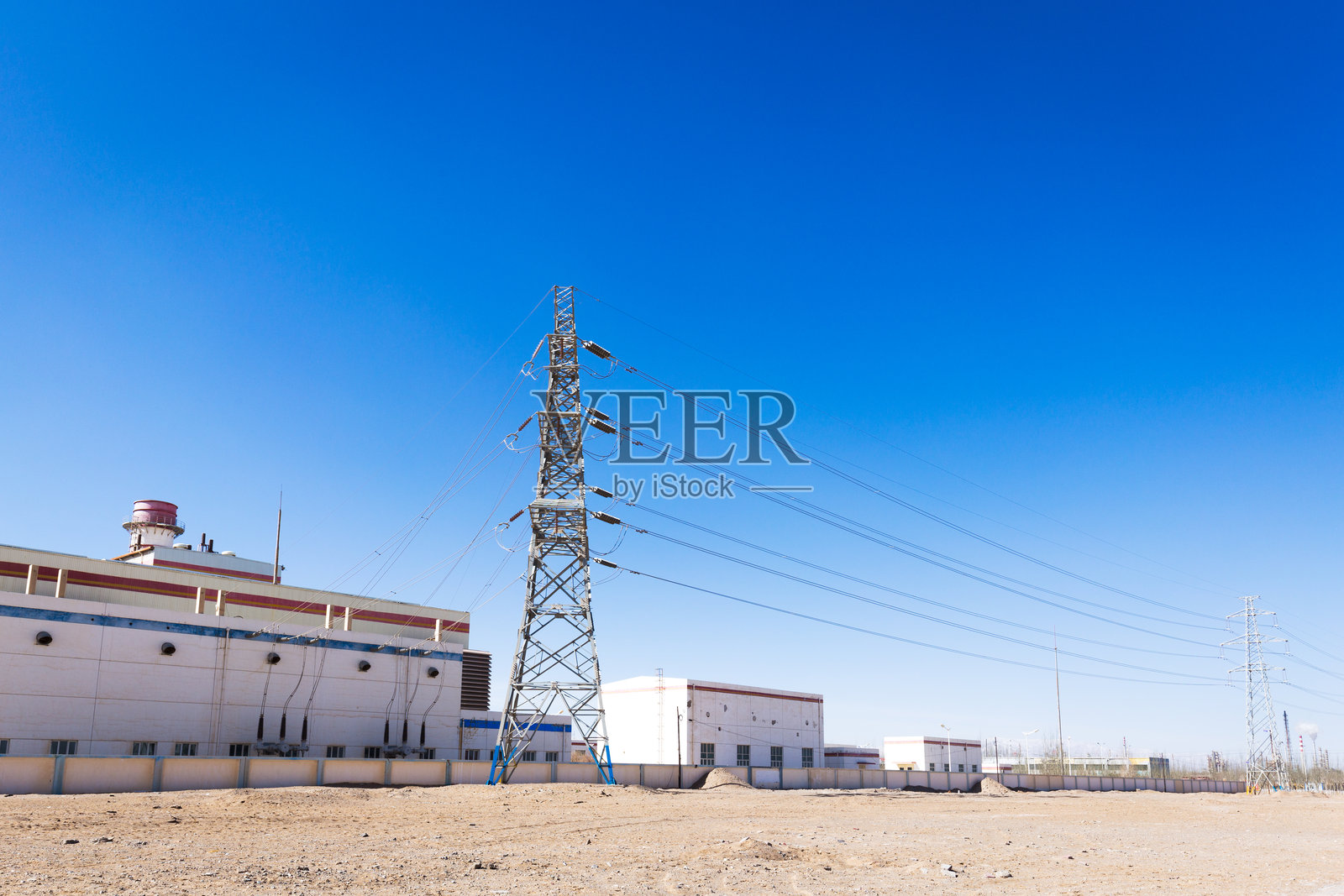 晴空下变电站与高压输电塔及荒漠厂房实景照片摄影图片