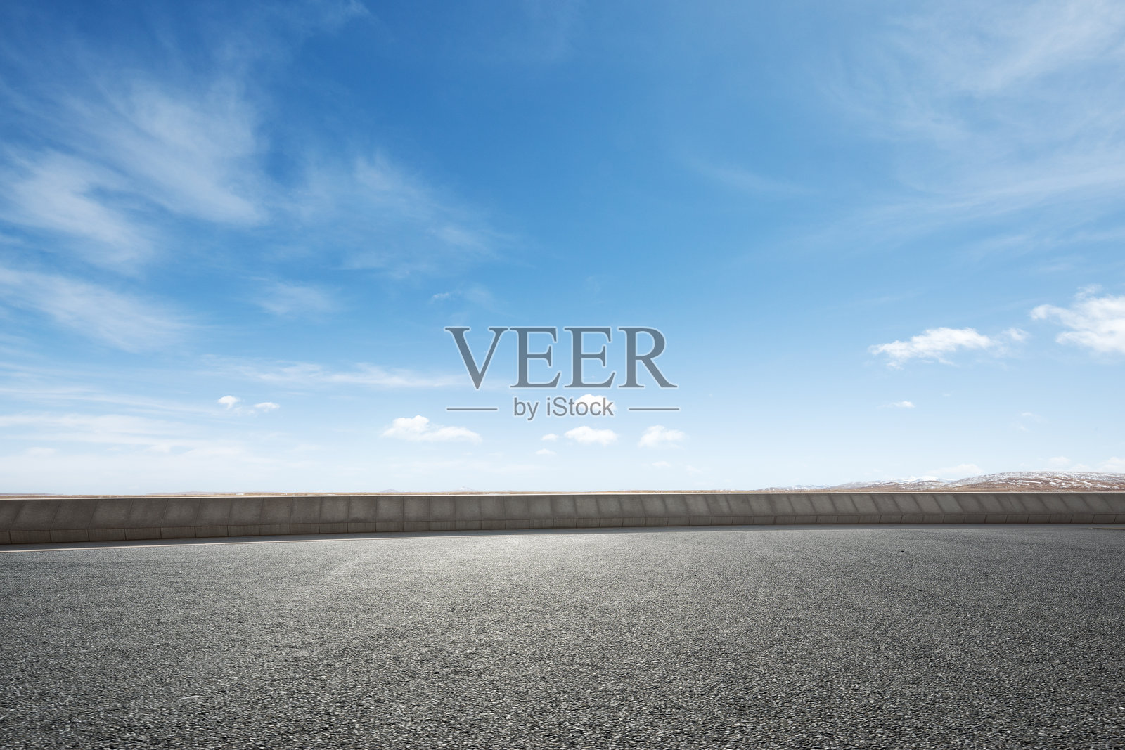 晴朗蓝天下的空旷沥青路面与混凝土护栏照片摄影图片