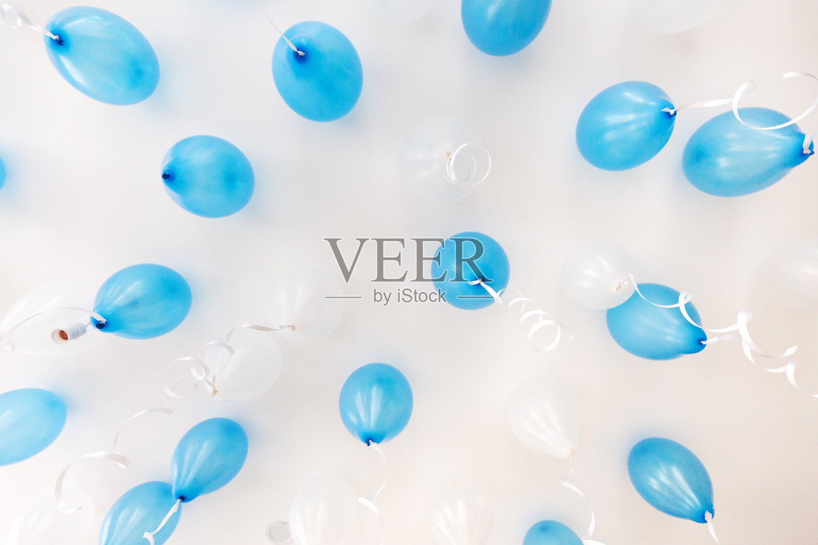 白色背景上漂浮的蓝色气球与白色丝带装饰照片摄影图片