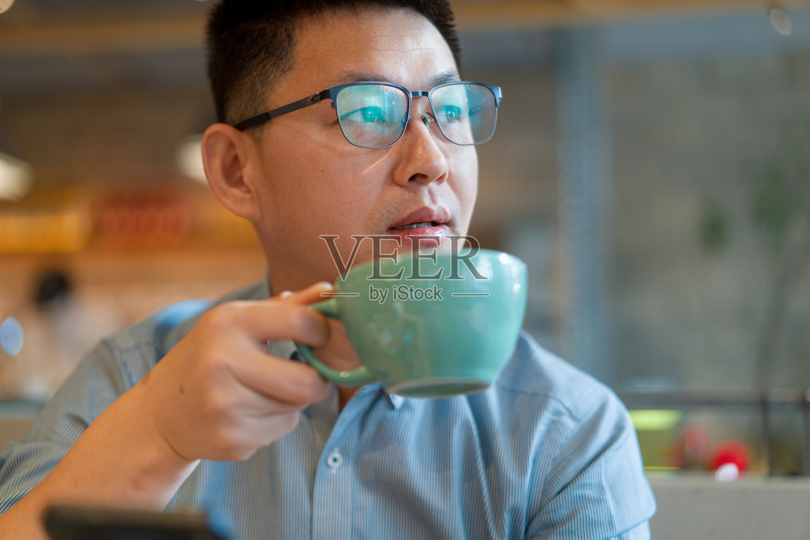 戴眼镜男子手持青瓷杯饮咖啡照片摄影图片