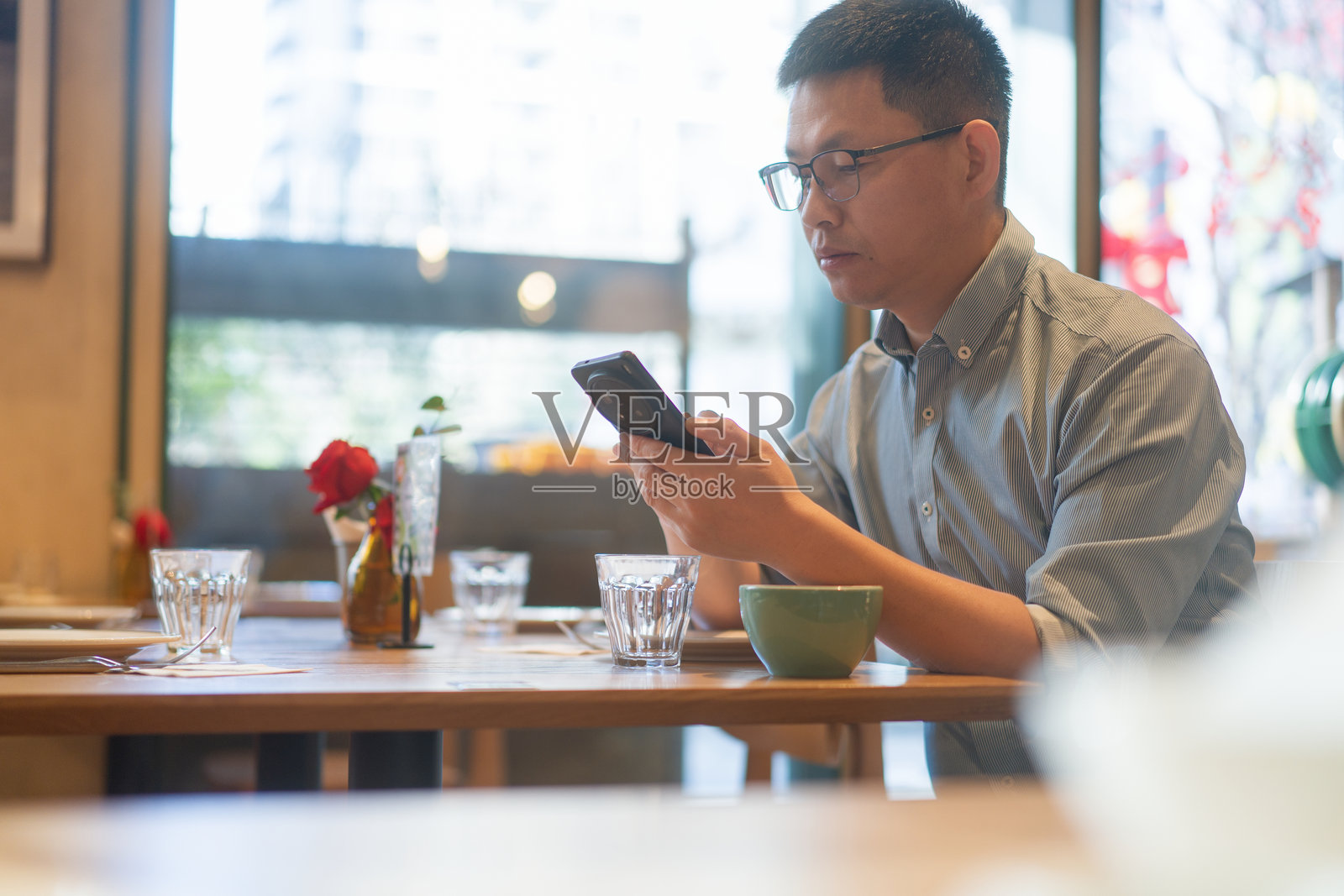 戴眼镜男子咖啡馆专注看手机照片摄影图片