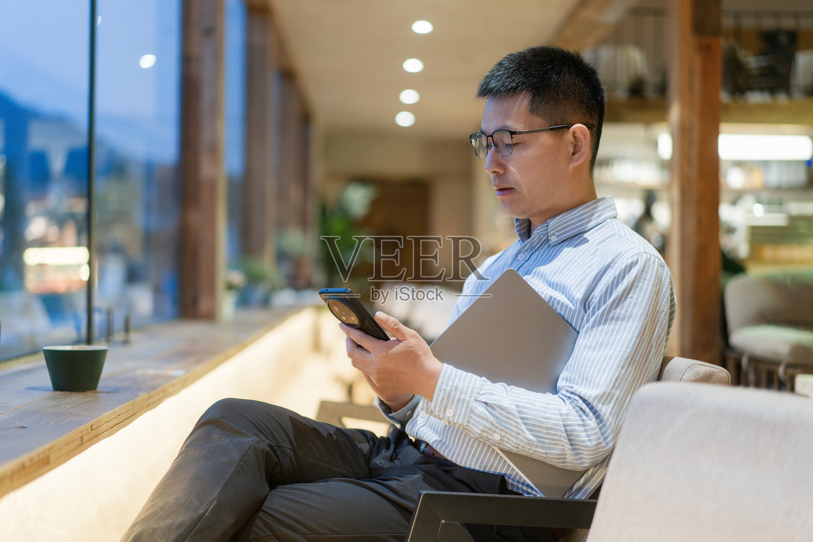 戴眼镜男子咖啡馆用手机看文件照片摄影图片