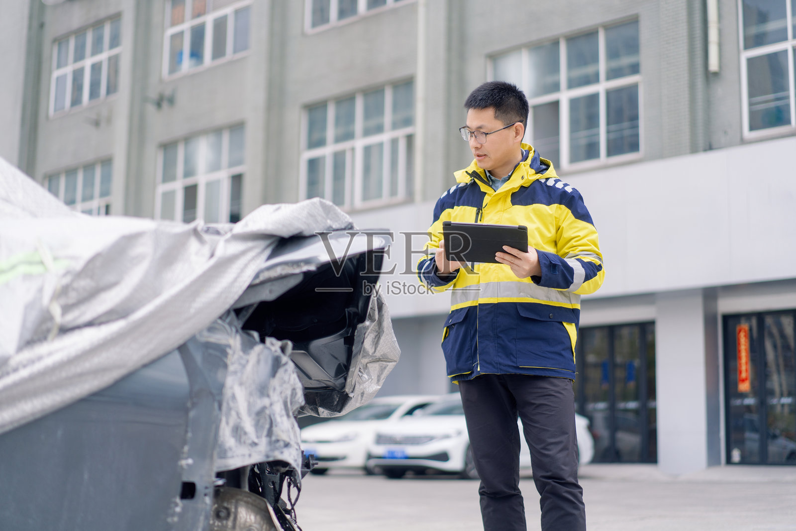 维修员手持平板检查受损车辆照片摄影图片