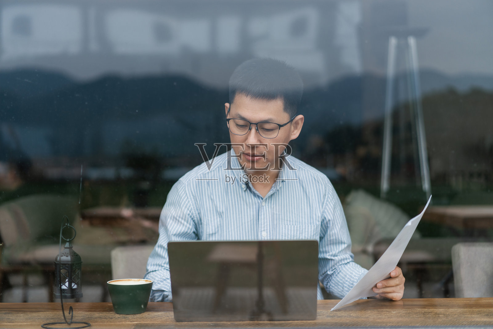 戴眼镜男子咖啡馆用笔记本看文件照片摄影图片