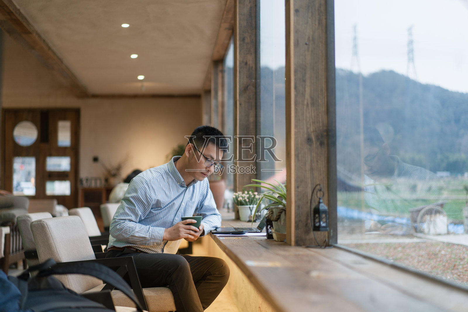 戴眼镜男子窗边咖啡馆专注看手机照片摄影图片