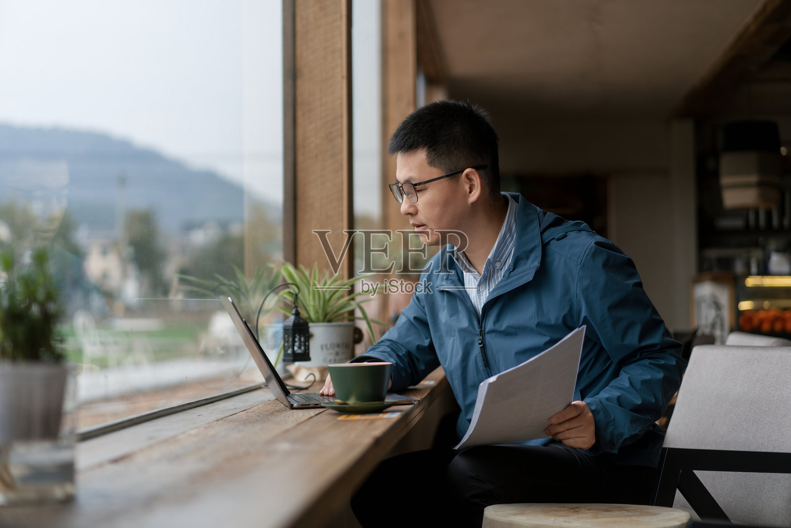 戴眼镜男子窗边用笔记本电脑工作照片摄影图片