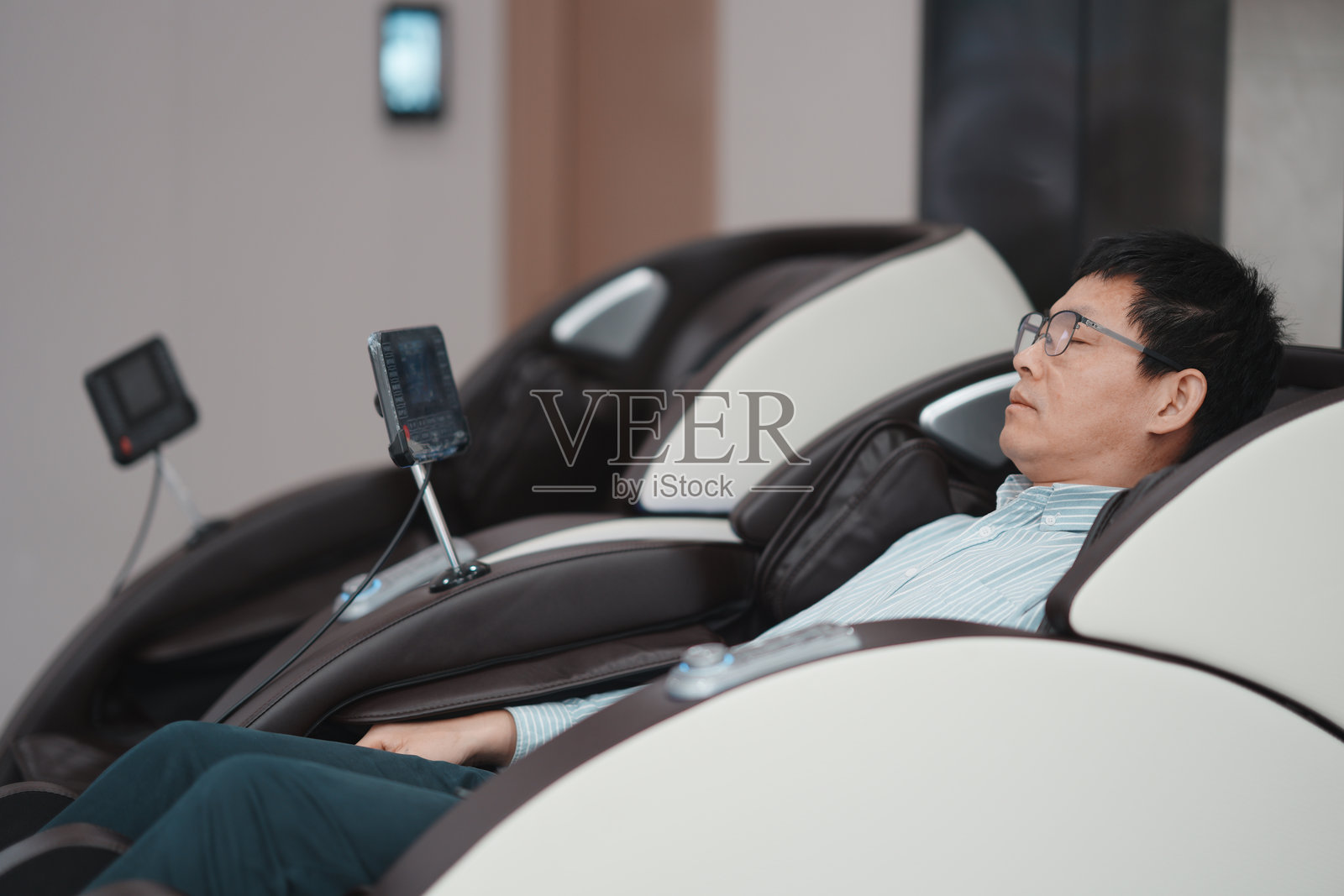 中年男子戴眼镜躺按摩椅放松休息照片摄影图片